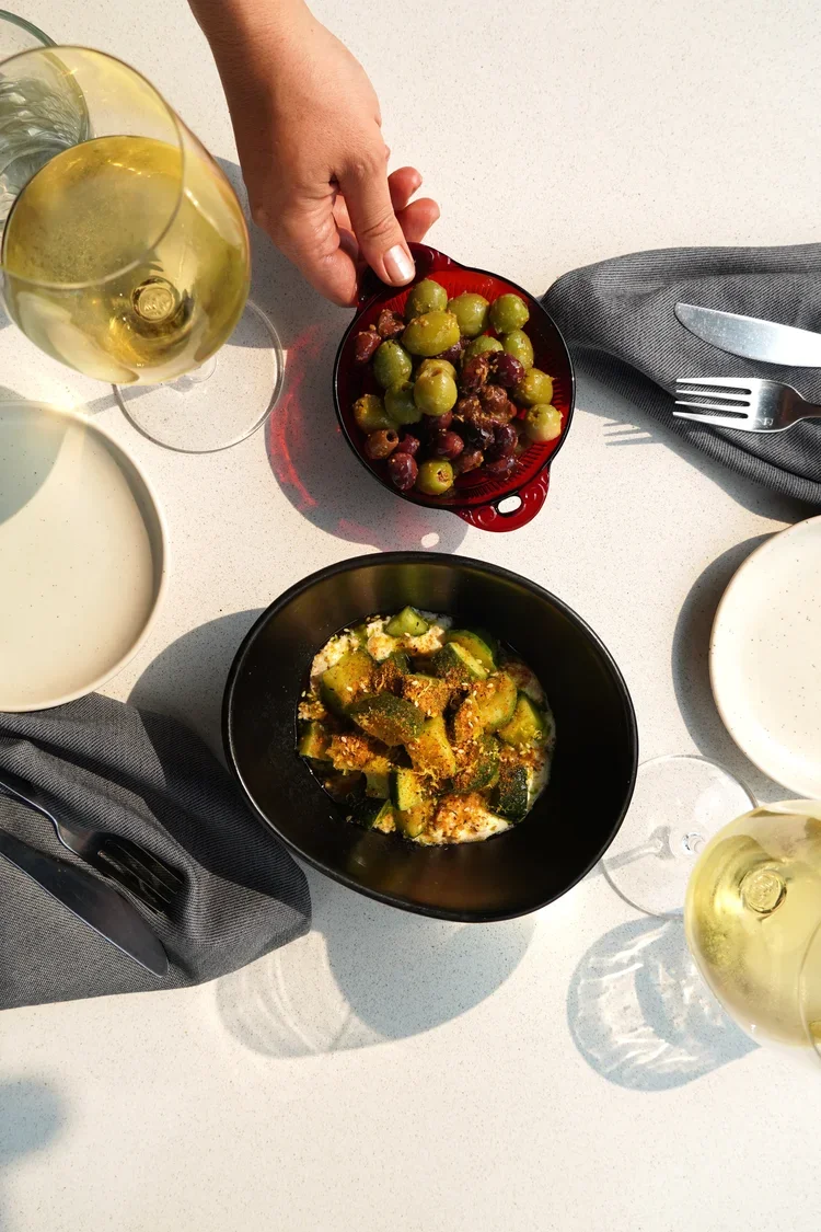 Chef serving a seasonal cucumber salad and olives tableside at Cork Restaurant — farm-to-table dining in Stowe, Vermont