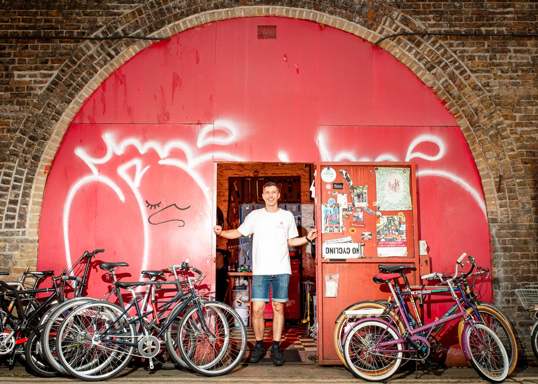 Dan standing in front of his railway arch bike shop in Haggerston London