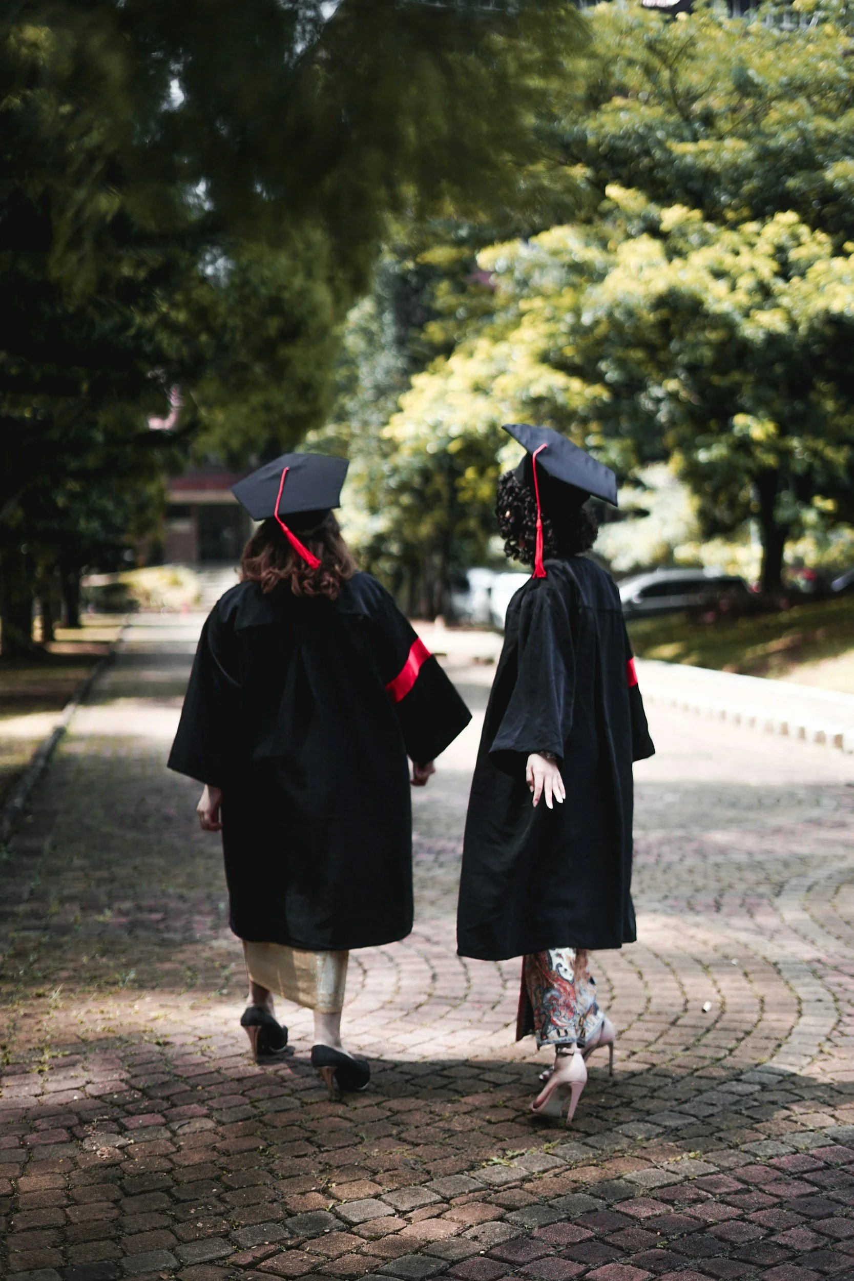 Two students in graduation outfits walking outside.