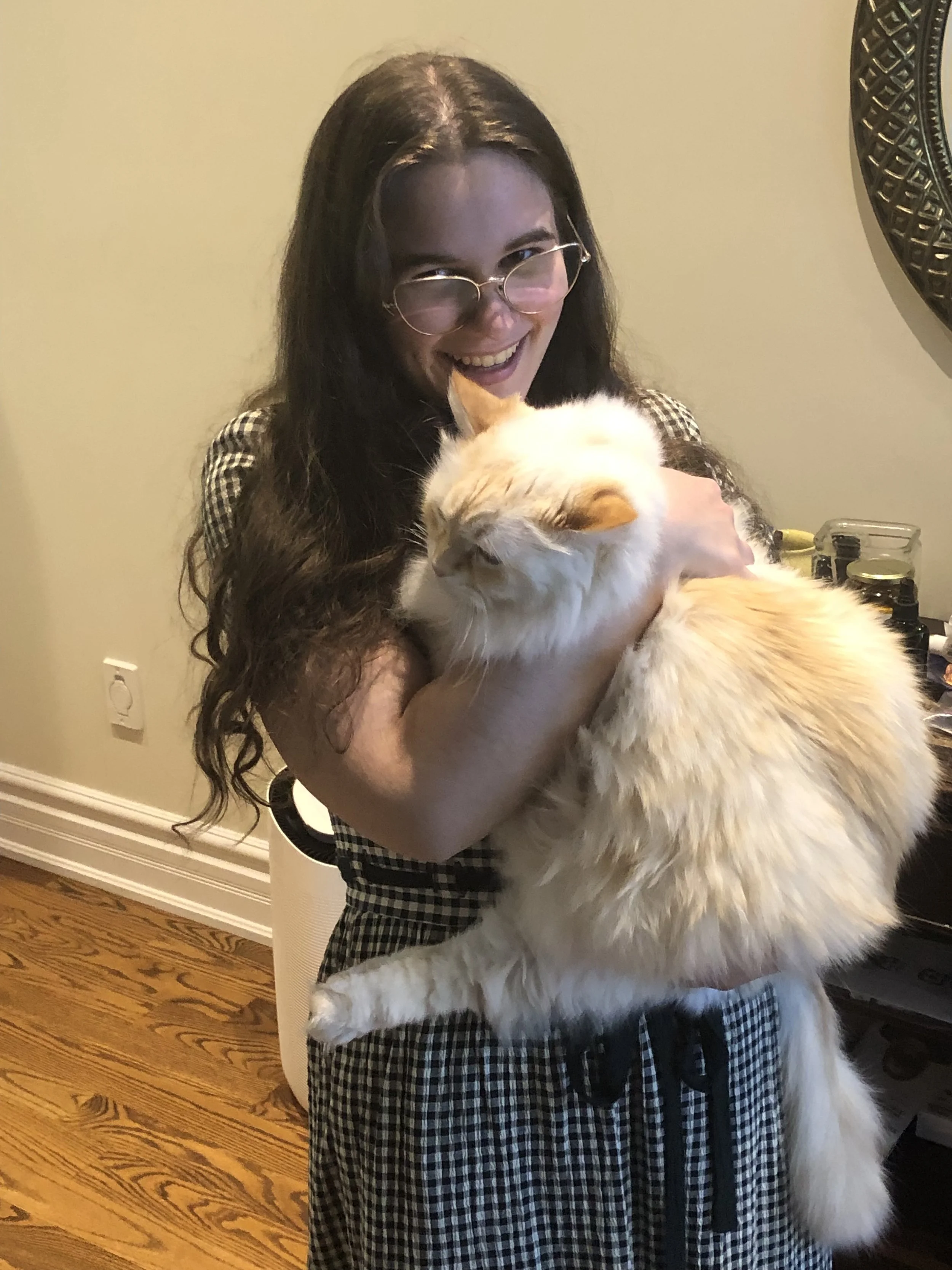 Zoe Lewis, certified ADHD coach in Toronto, is a white woman with long brown wavy hair and glasses.  She is holding her flame-point long haired cat.