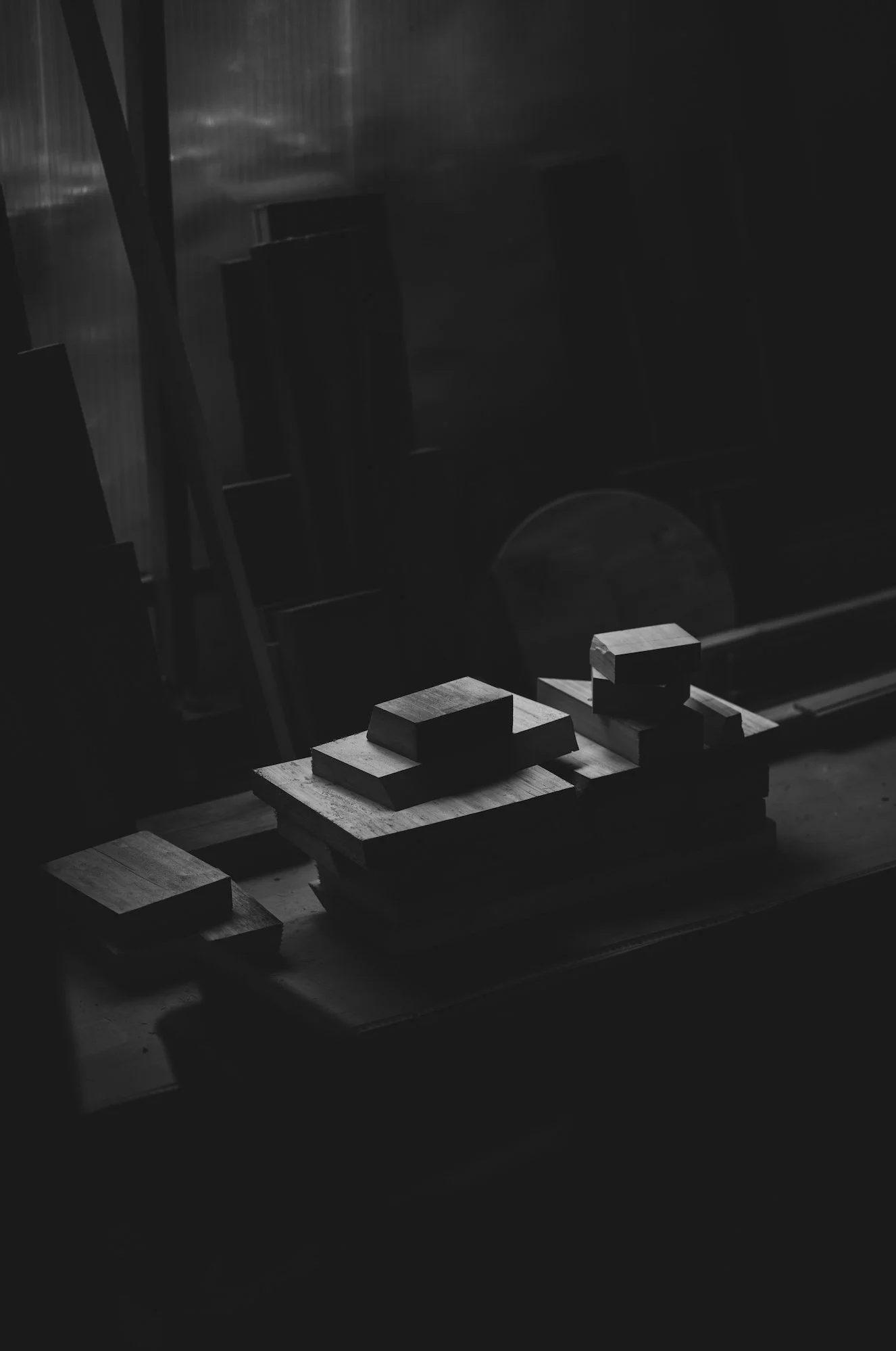 Black and white photo of wooden blocks arranged on a work surface, possibly a woodworking or carpentry shop.