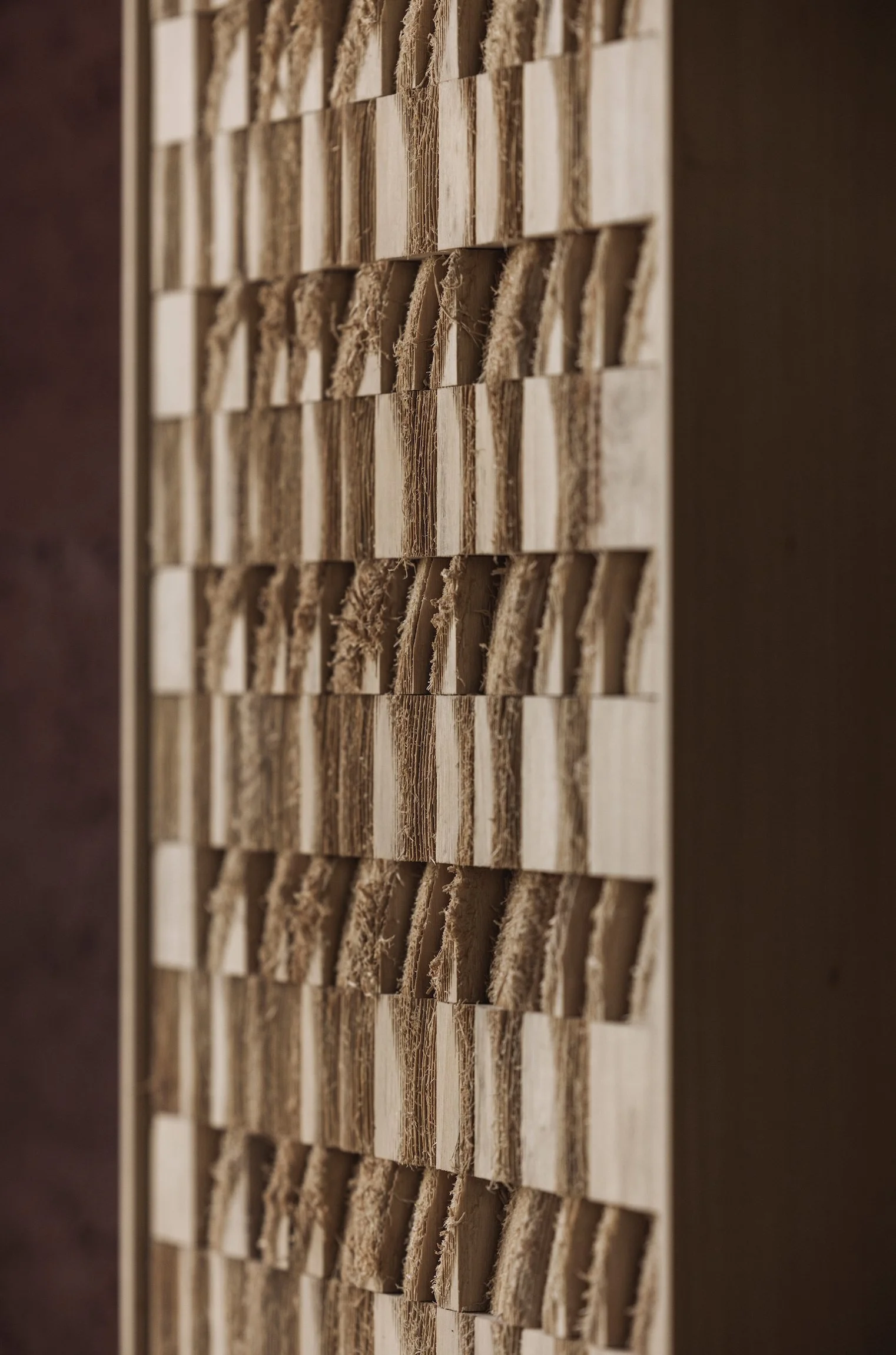A close-up view of a speaker grill with small, square wooden blocks arranged in a grid pattern, with some blocks showing frayed or worn edges.
