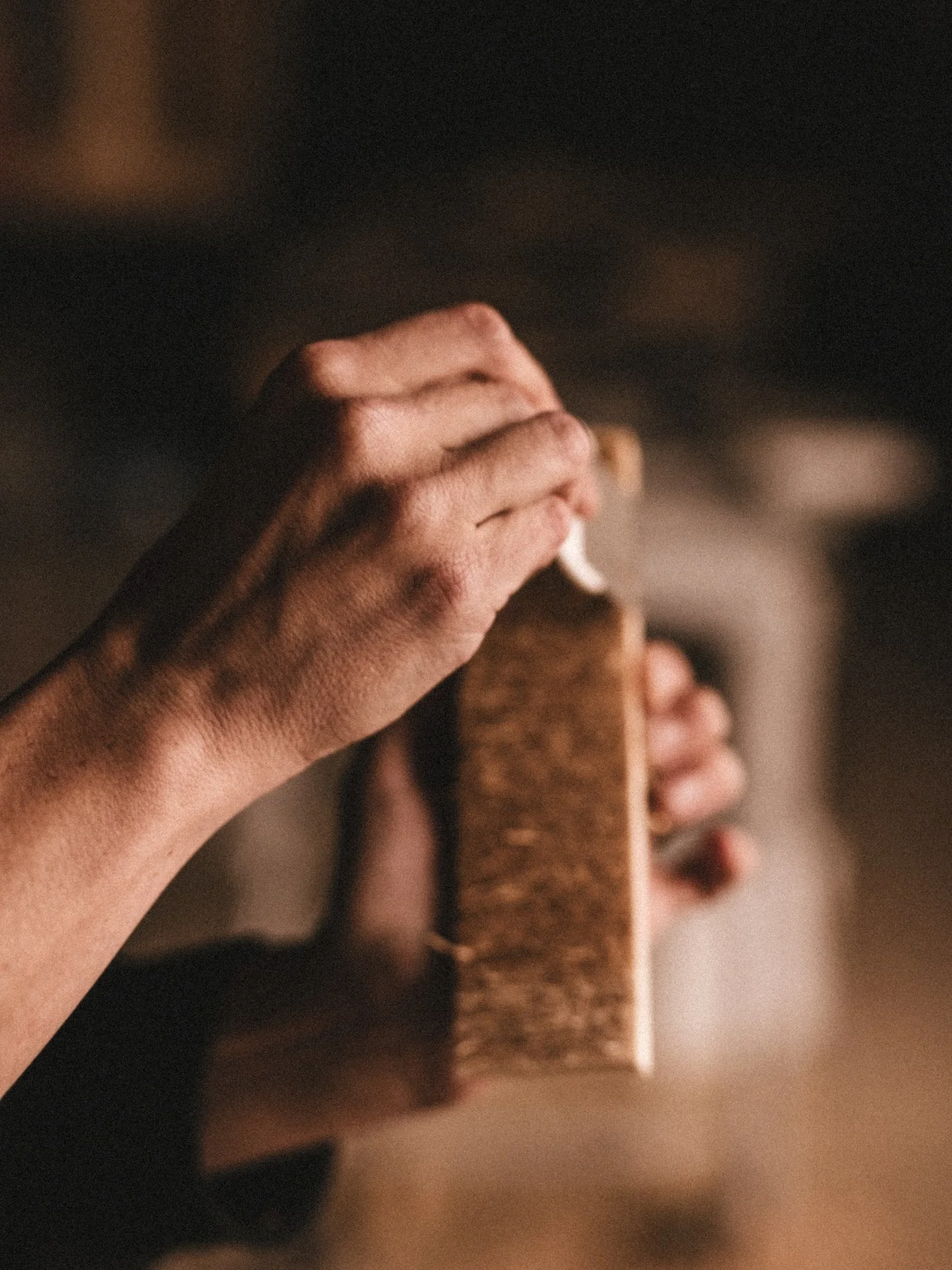 Close-up of a person's hand holding a toasted bread slice, with blurred background.