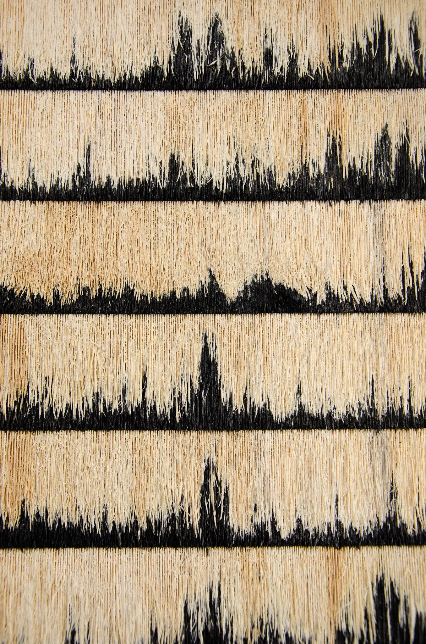 Close-up of a paintbrush with beige and black bristles, showing worn bristles and paint residue.