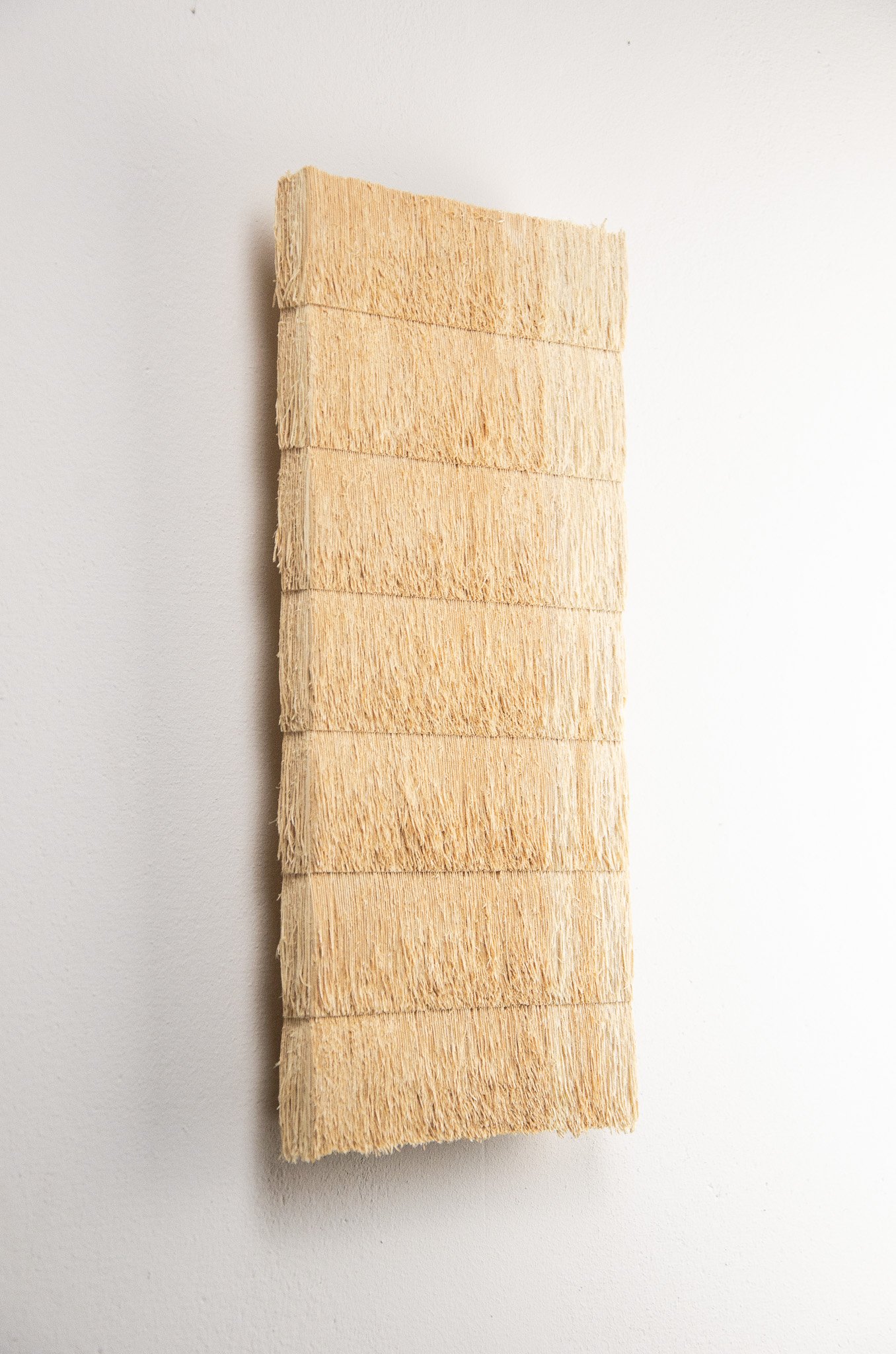 A vertical stack of four natural-colored wooden skirting or molding pieces with a rough texture on a white background.