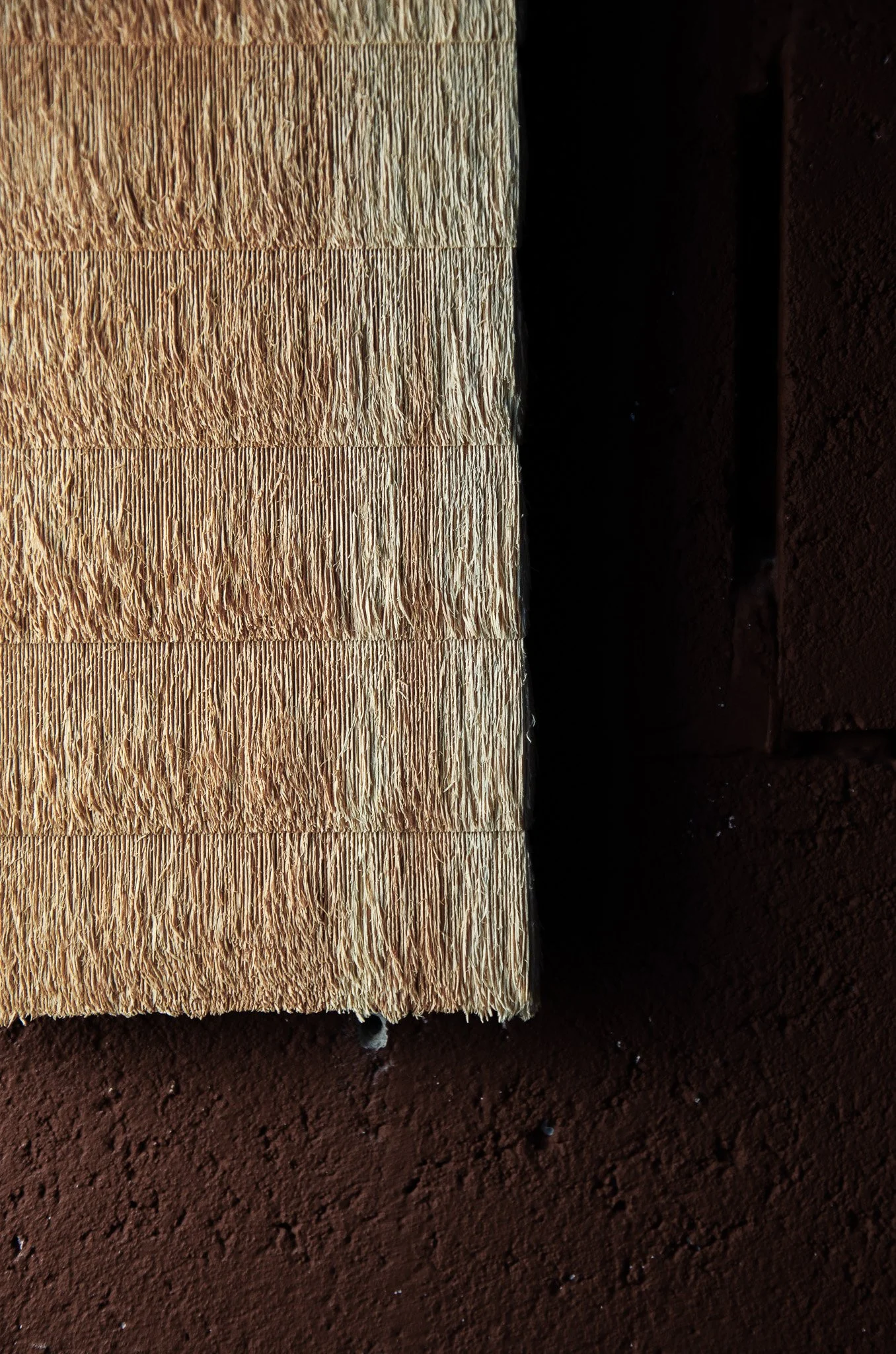 Close-up of a section of wood siding with horizontal planks showing texture and grain, against a dark, textured background.