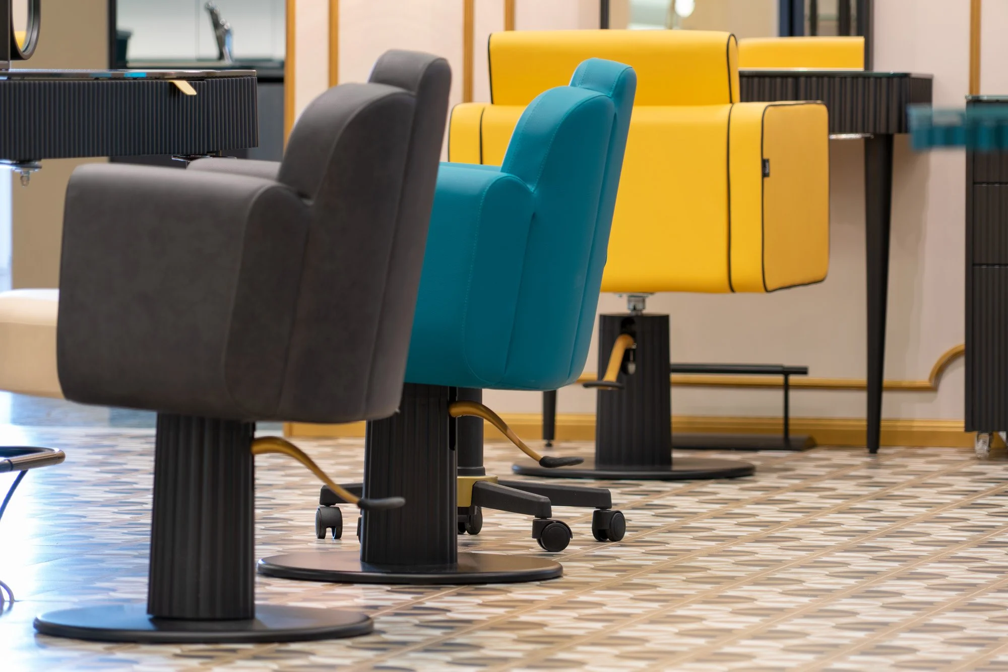 Série de fauteuils de bureau de différentes couleurs dont le noir, le turquoise et le jaune, dans un espace de bureau moderne.