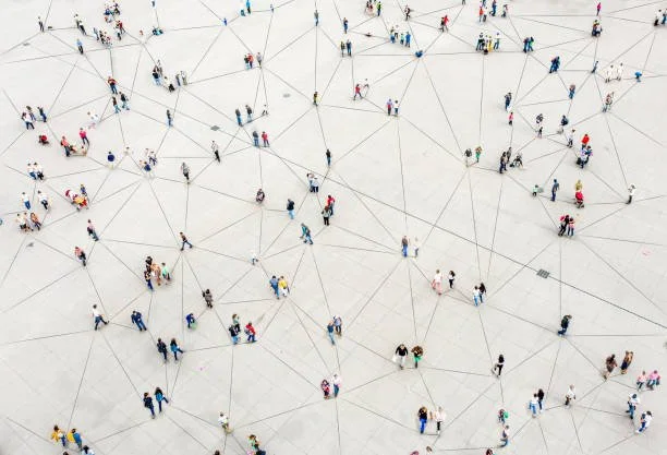 Bird's eye view of numerous people walking on a large, open, white surface connected by lines, creating a network pattern.