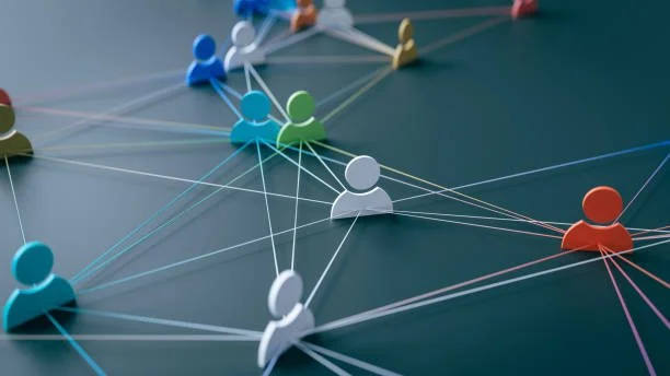 Illustration of various colored paper cutouts representing people connected by lines, symbolizing a network or social connections.