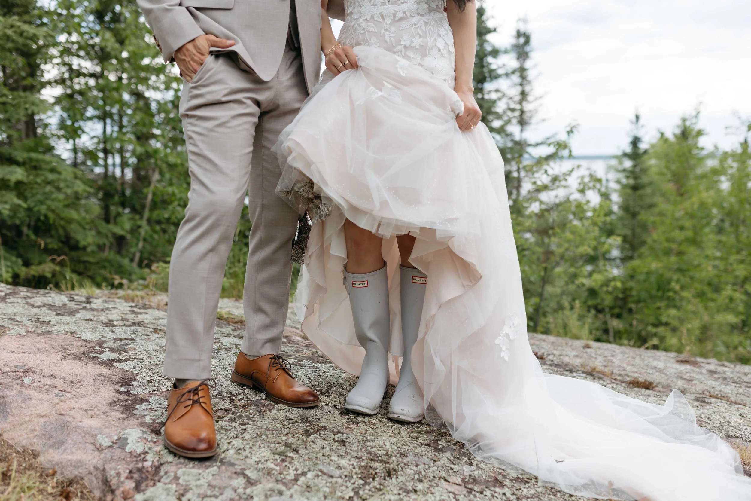 Close-up of a bride and groom standing outdoors on a rocky surface with trees in the background in Winnipeg