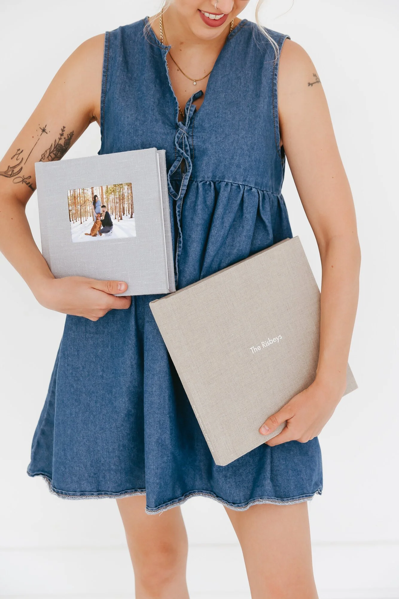 Photographer holding custom albums of a Winnipeg family and a Winnipeg couple displaying their maternity photos