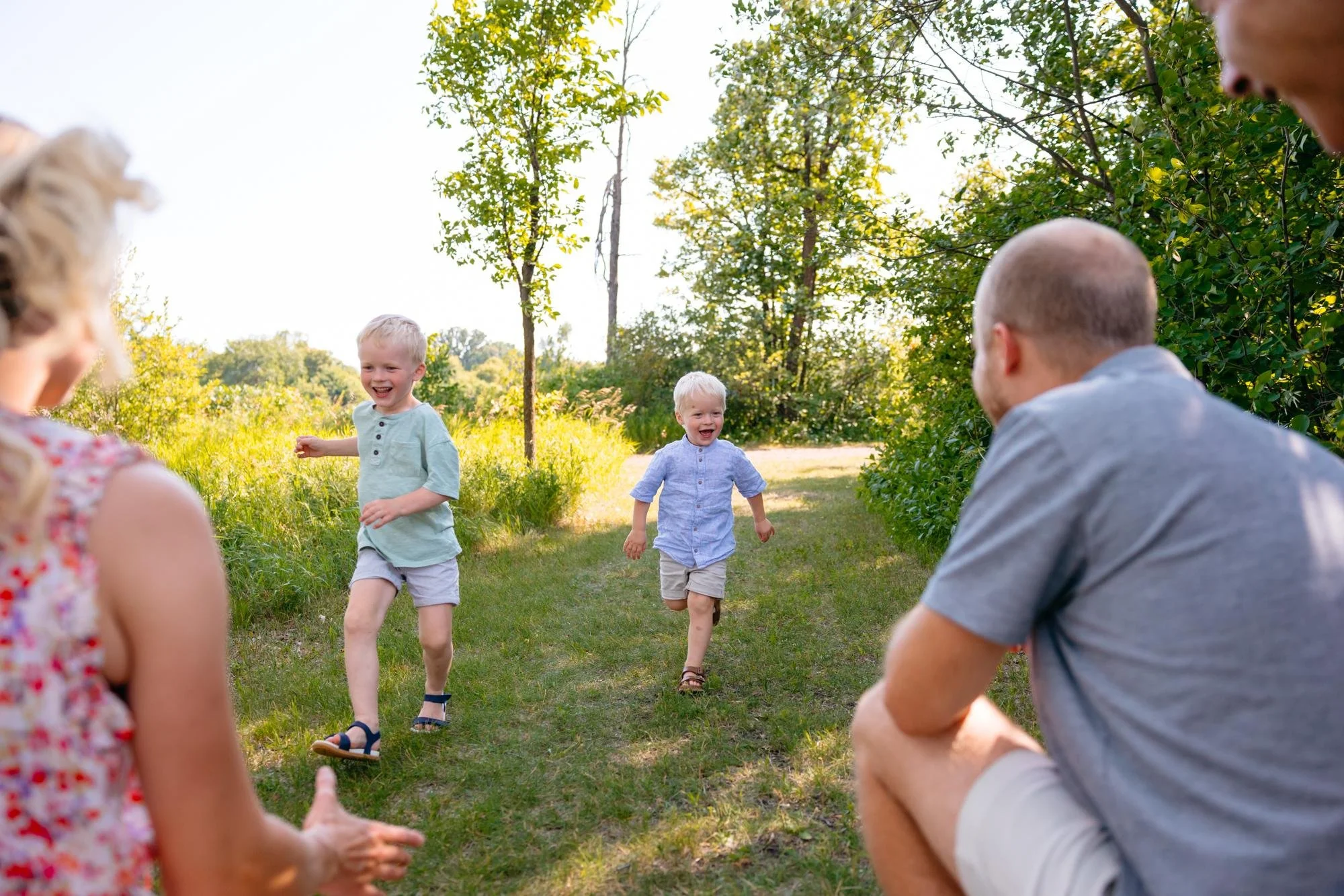 Children running and laughing outdoors during a winnipeg family session with Sari Risbey photography