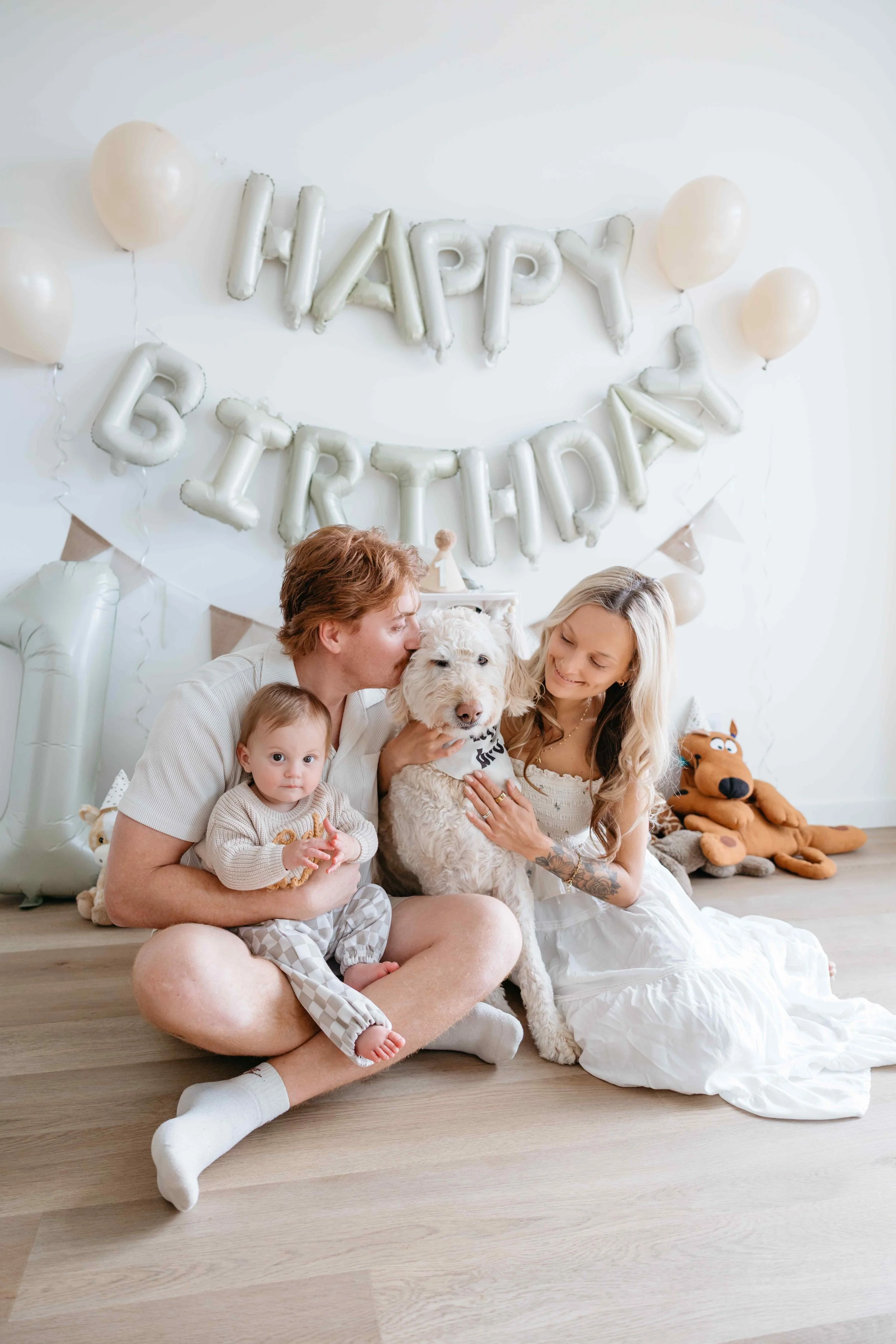 A family of three with a dog celebrating a birthday in a decorated room in Winnipeg.