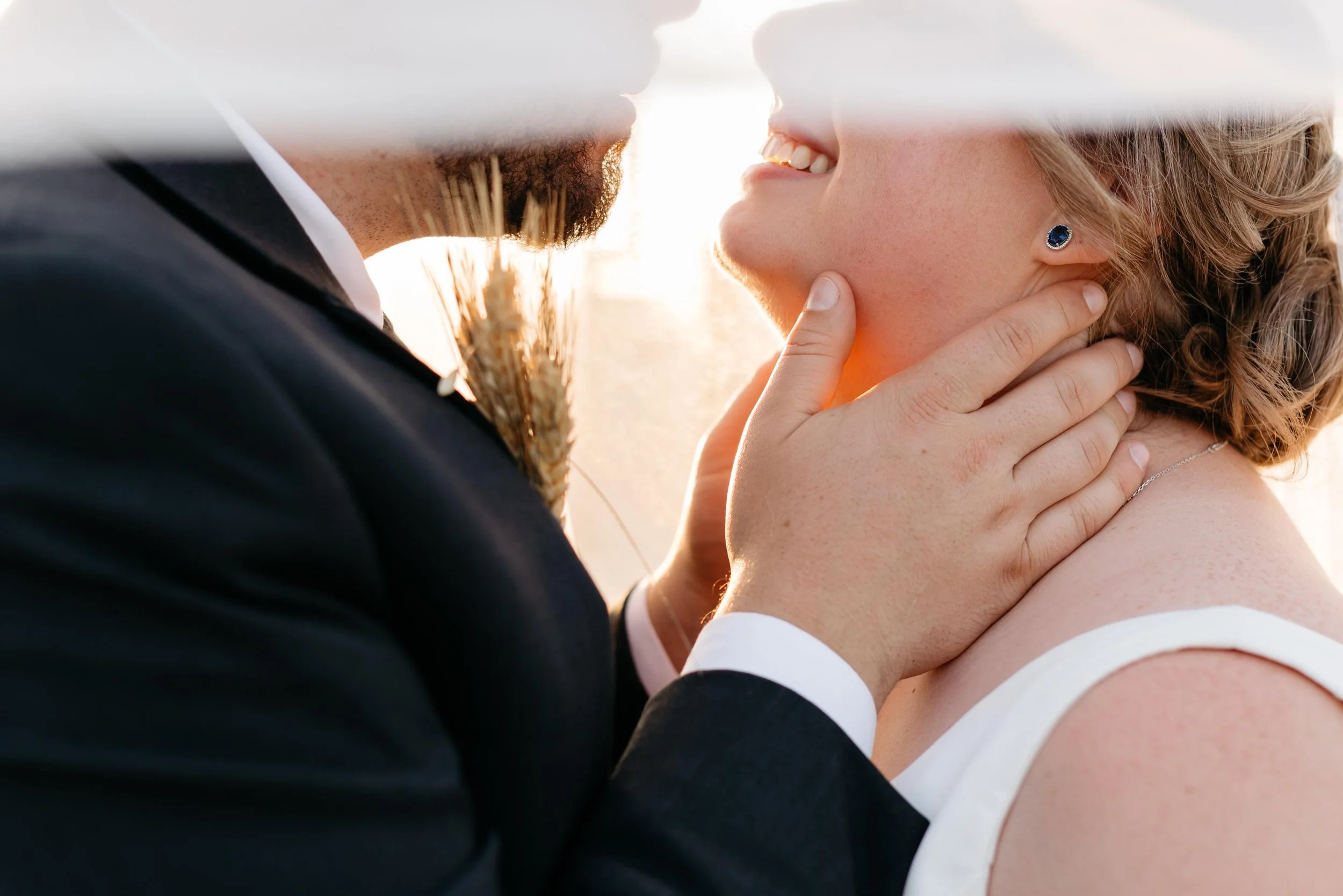 A close-up of a couple touching foreheads and smiling, with sunlight in the background, capturing a happy moment.