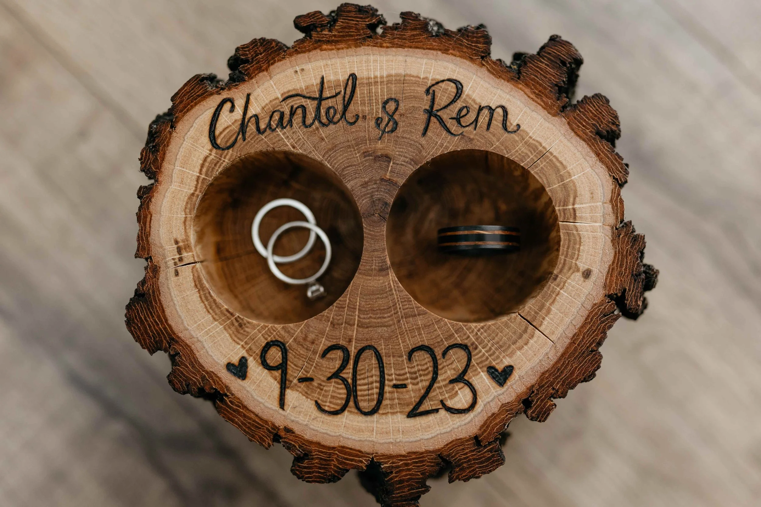 Close-up of a cross-sectioned tree trunk with engraved text, a date, and two rings inside.