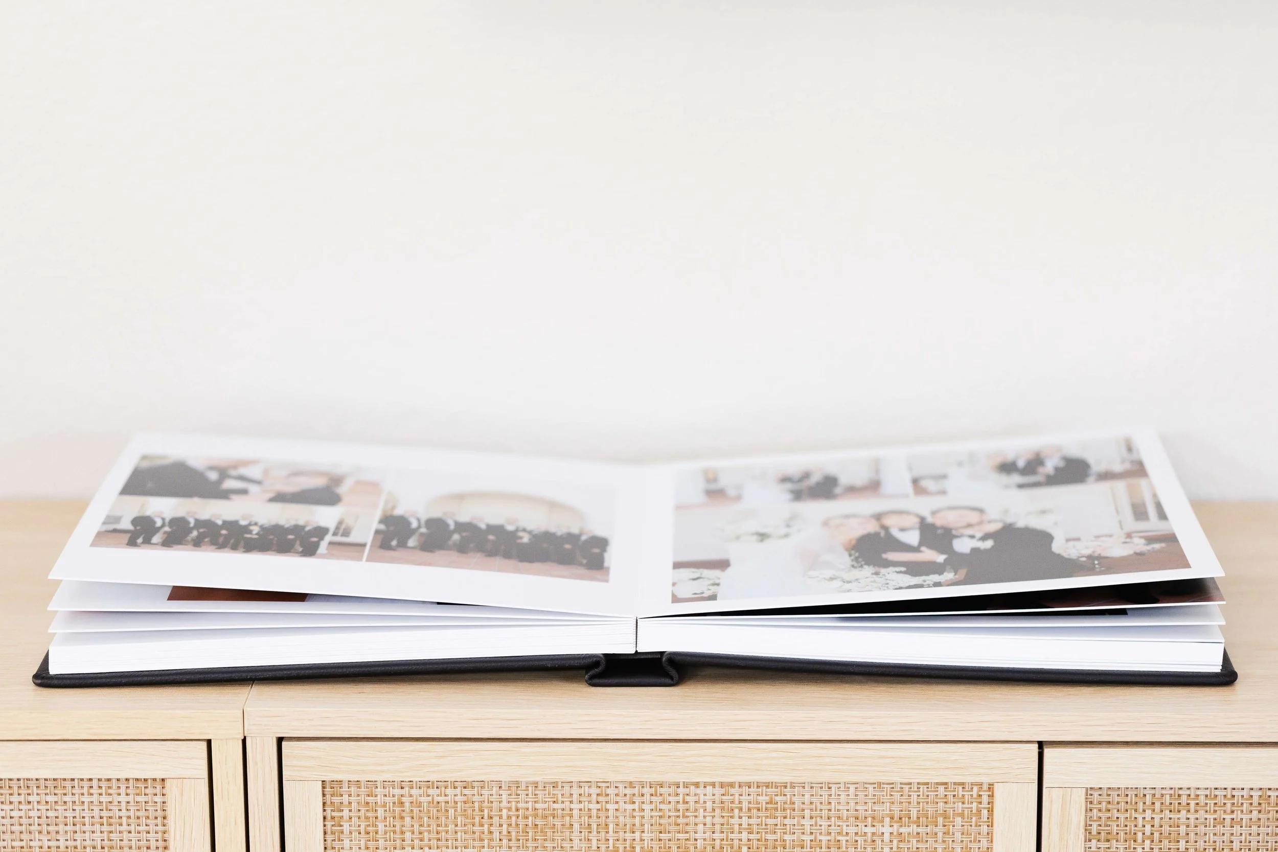 An heirloom album with multiple pages displaying photographs, placed on a wooden table.