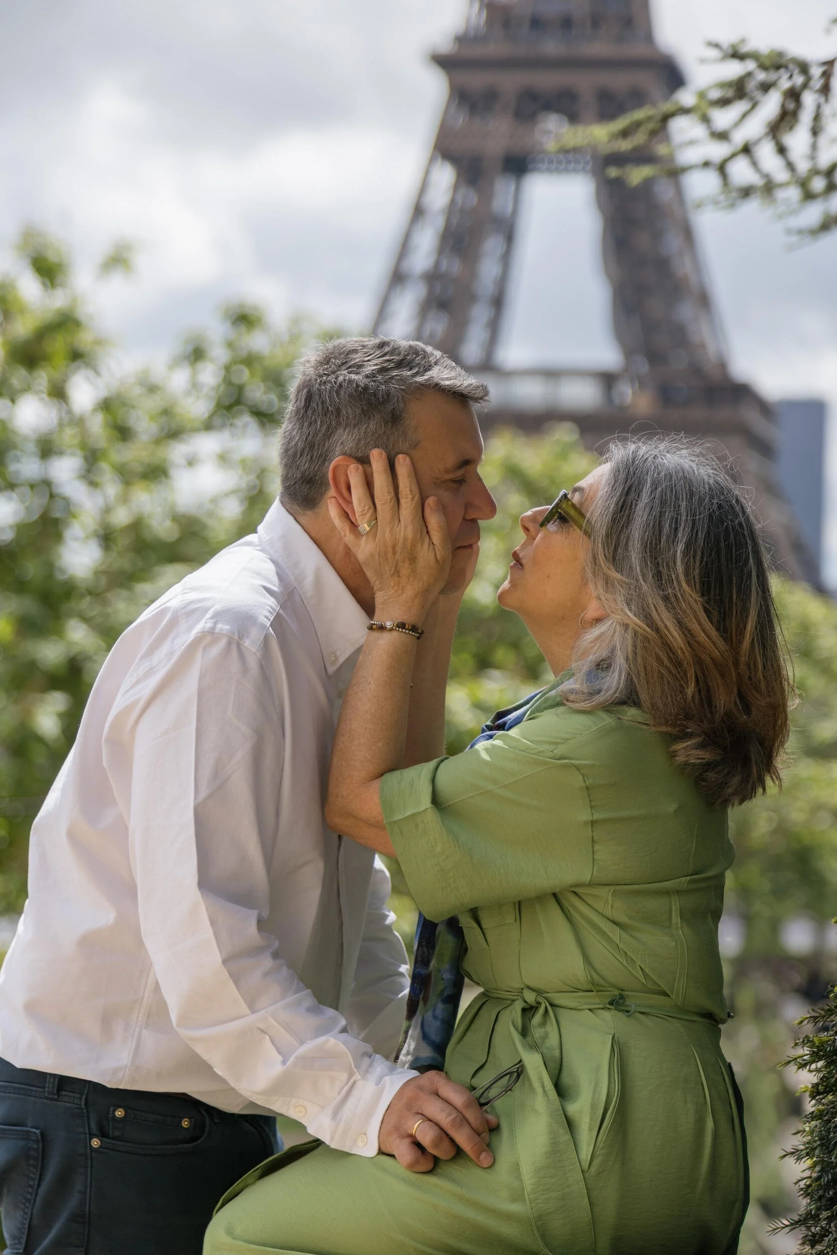 A couple looking into each other's eyes while holding hands outdoors near the Eiffel Tower.
