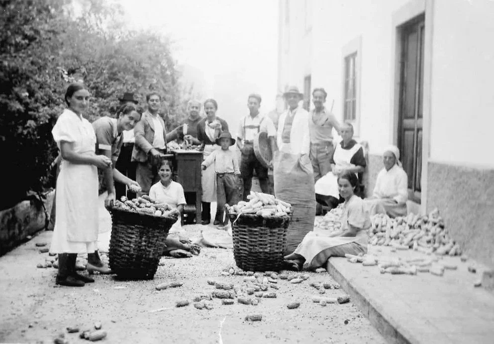 Grupo de personas vendiendo y comprando pan y otros productos en la calle, en un entorno rural.