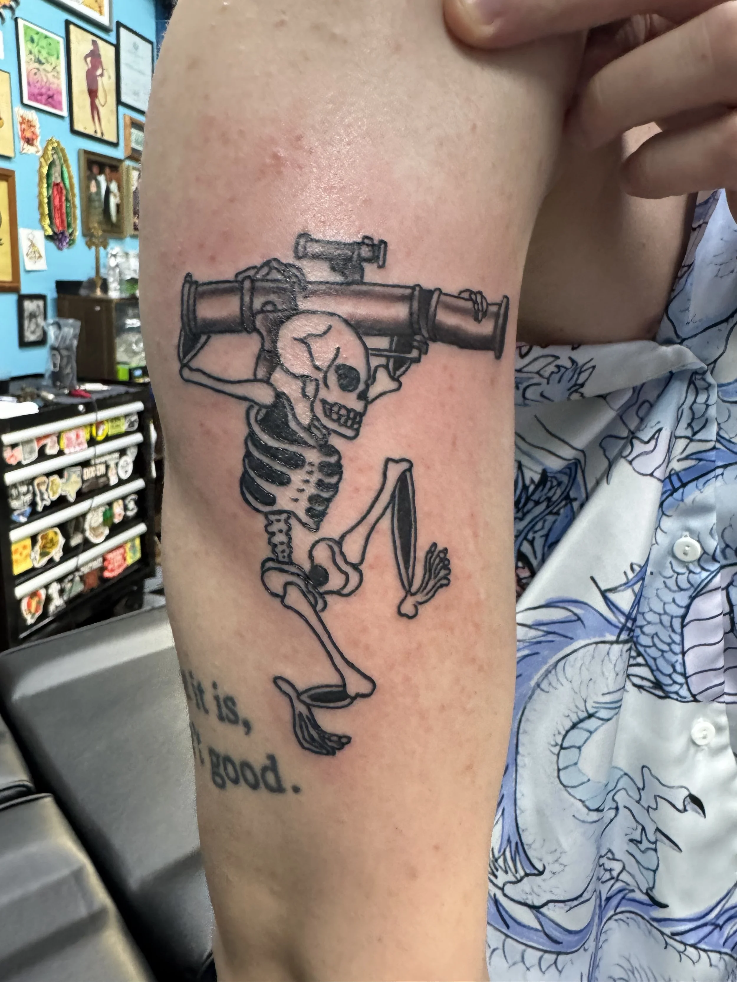 A tattoo of a skeleton holding a bazooka on a person's upper arm.