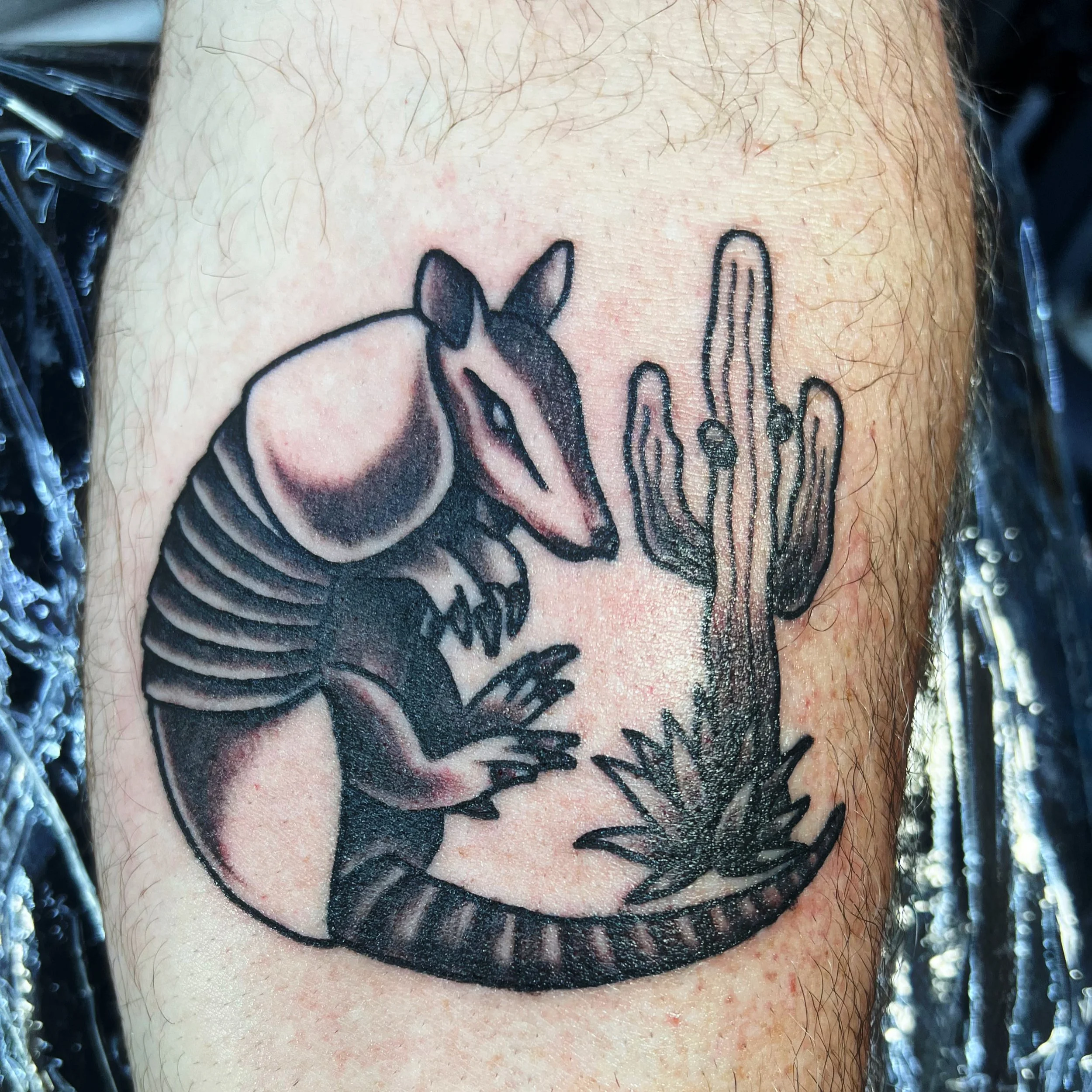 A tattoo of a stylized armadillo on a person's arm.