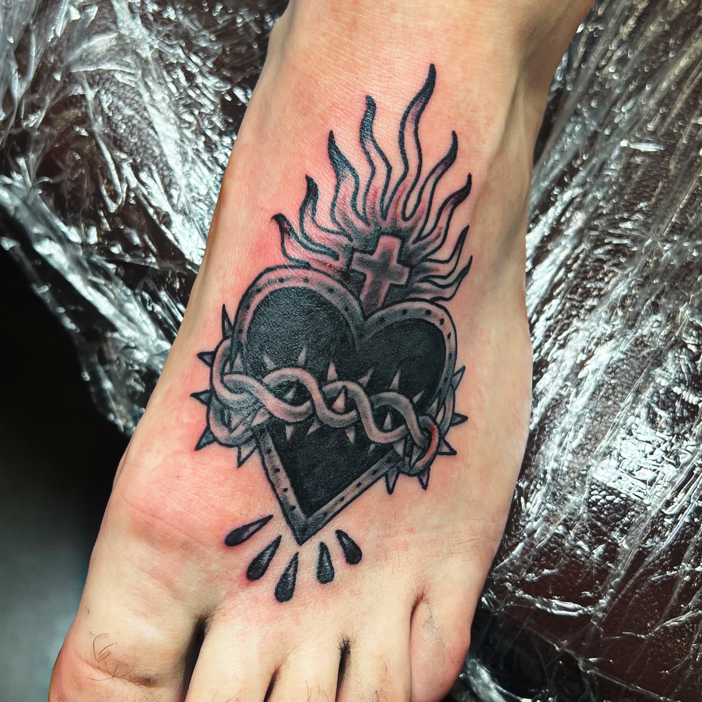 A tattoo of a sun with rays on the side of a person's foot.