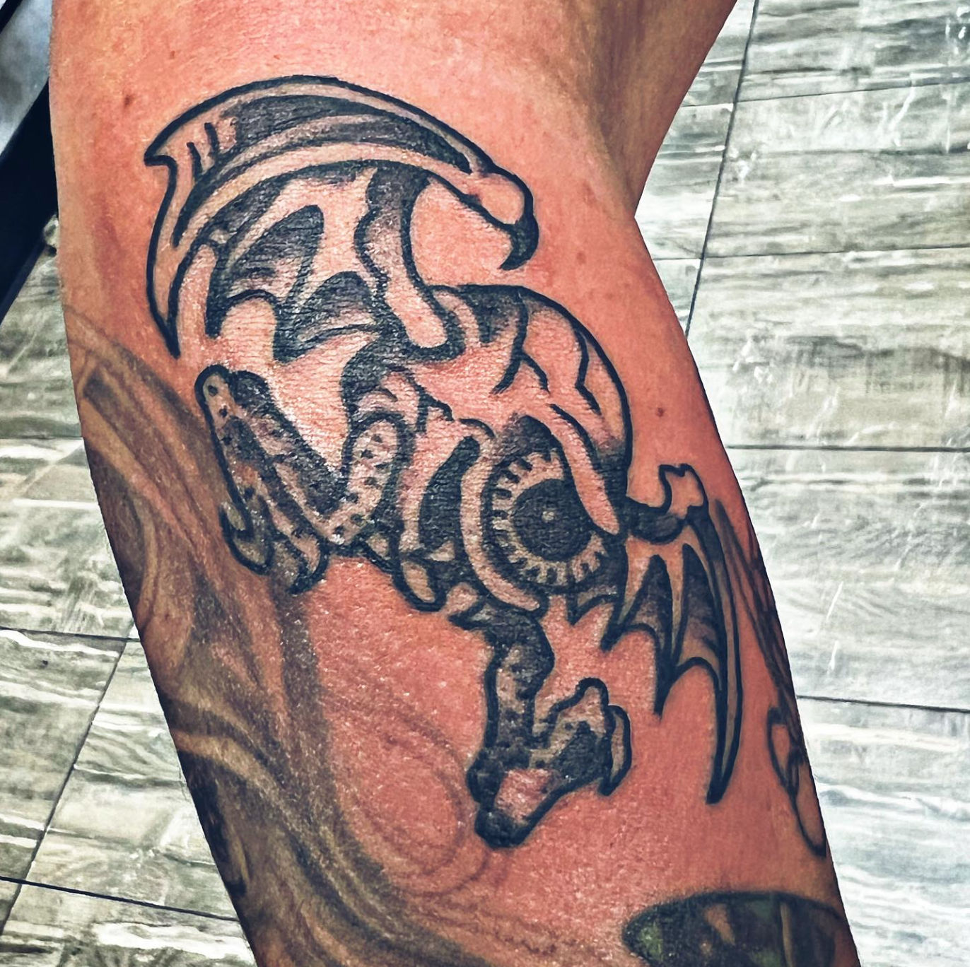 Tattoo of a eyeball monster with wings on a person's arm.