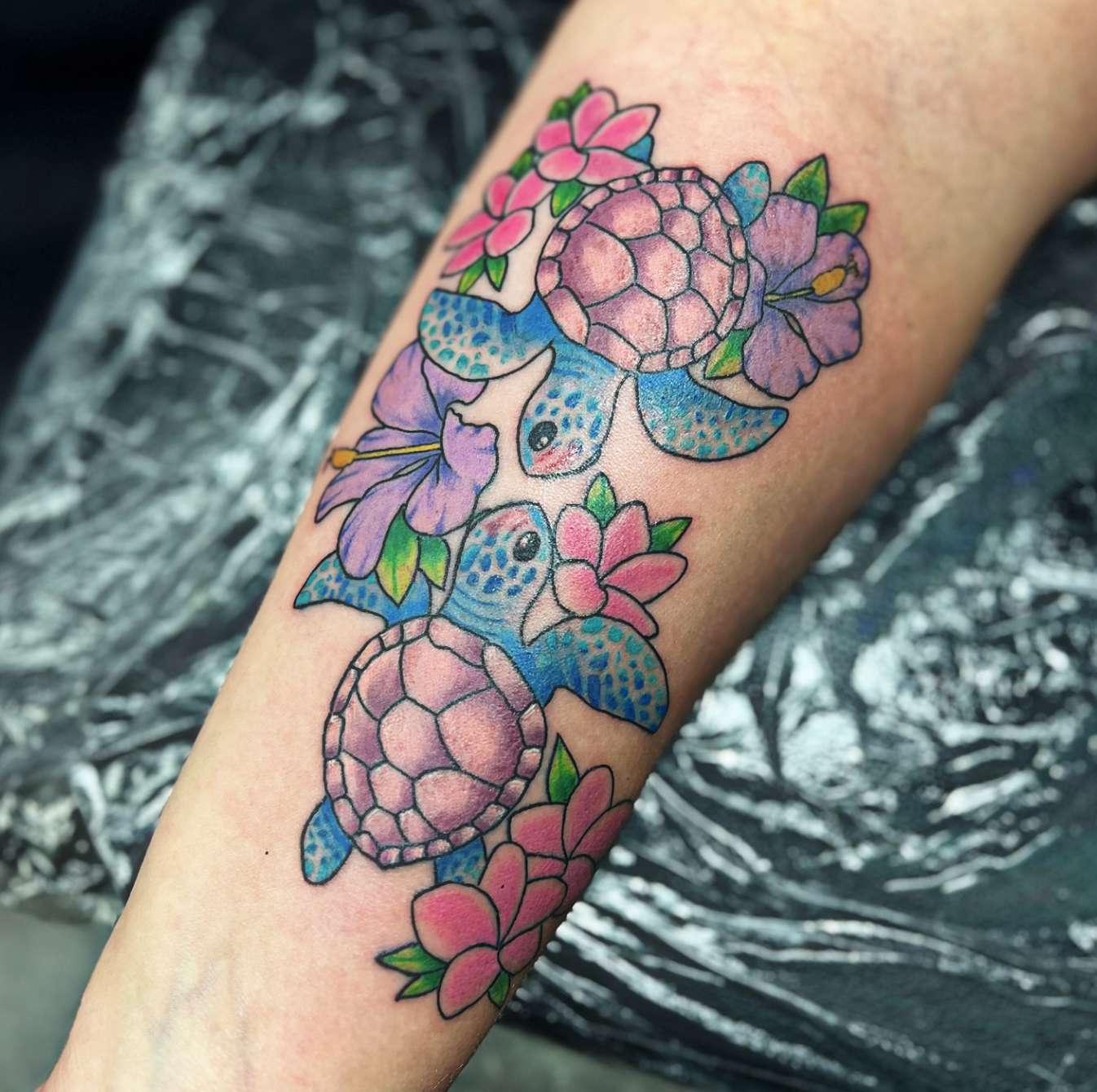 Colorful tattoo of two blue butterflies and pink flowers on a person's arm
