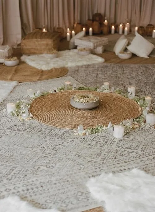 Cozy indoor setting with candles, pillows, and rugs arranged for a relaxing or meditation space.