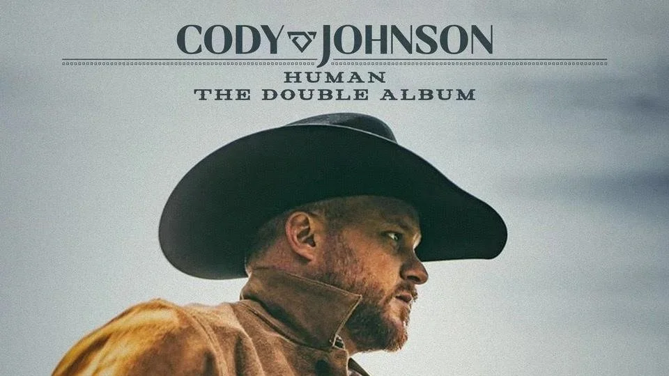 Justin Ostrander, Guitar Credits for Album cover for Cody Johnson's 'Human: The Double Album' featuring a side profile of a man wearing a black cowboy hat and brown leather jacket against a cloudy sky background.