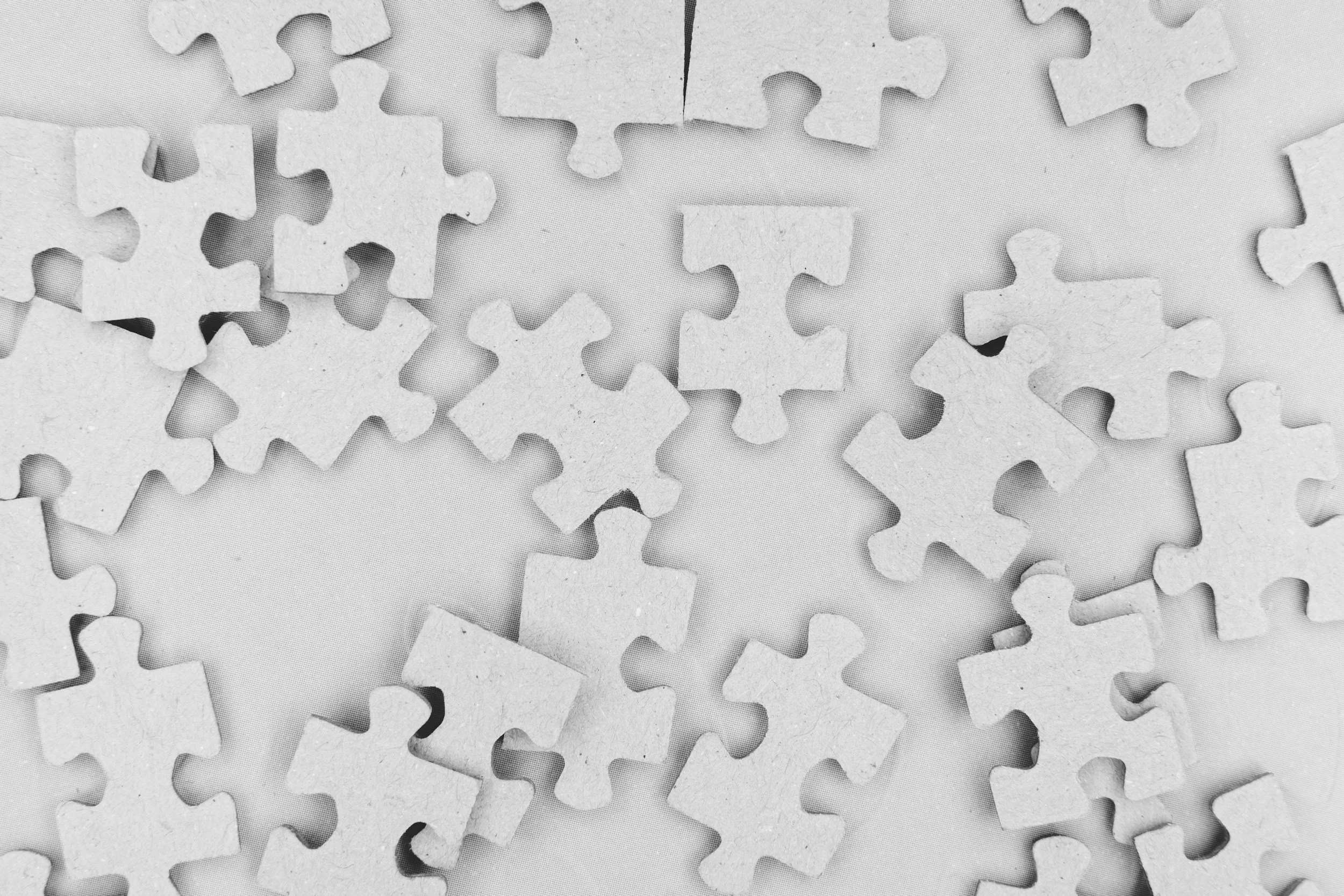 Scattered white puzzle pieces on a light surface.