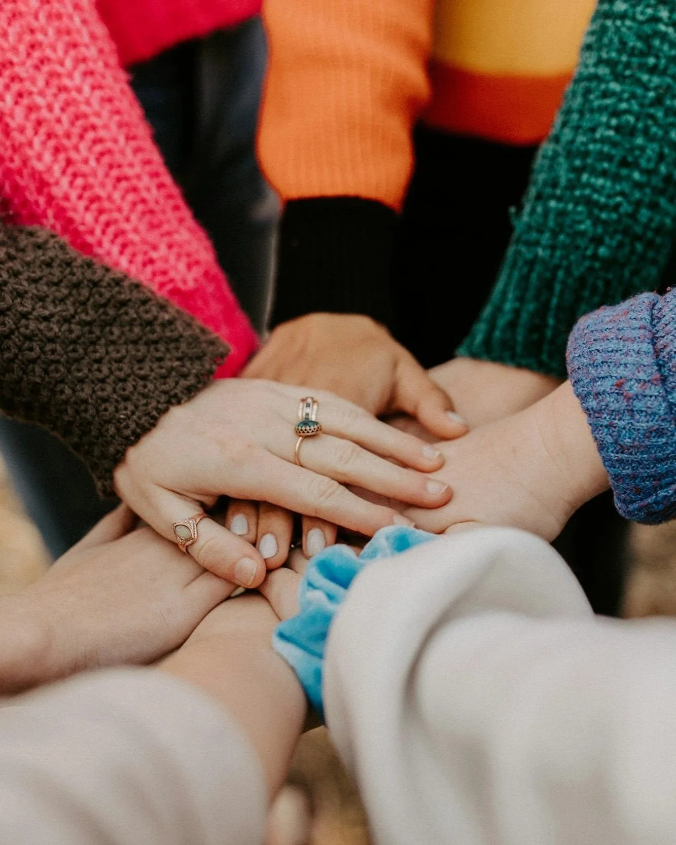 Multiple hands of different individuals stacked on top of each other, symbolizing unity or support.