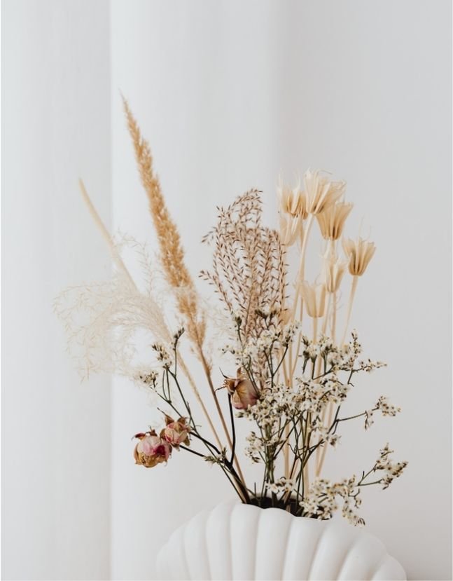 Dry floral arrangement with pampas grass, roses, and wildflowers in a white vase.