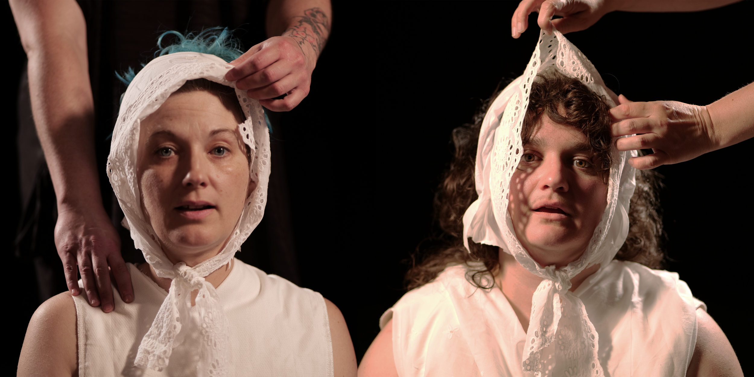Two white non-binary people gaze at us with pleasure as two pairs of hands arrange their baby bonnets.