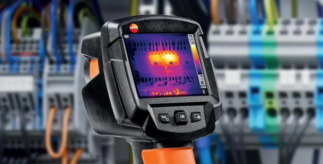 Infrared camera used to inspect electrical components with circuit breakers in an electrical panel.