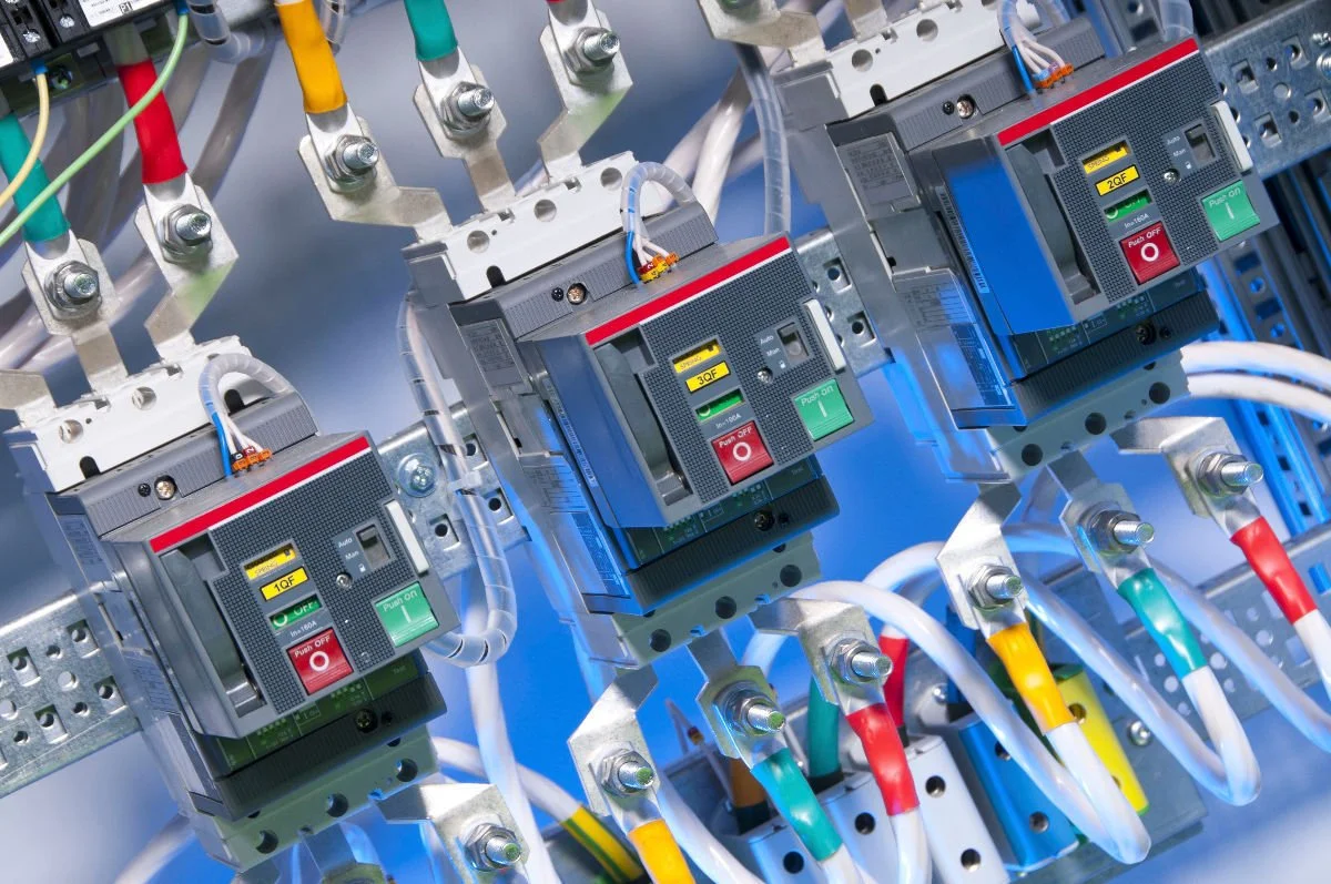 Close-up of industrial electrical components including circuit breakers and wiring in an electrical panel.