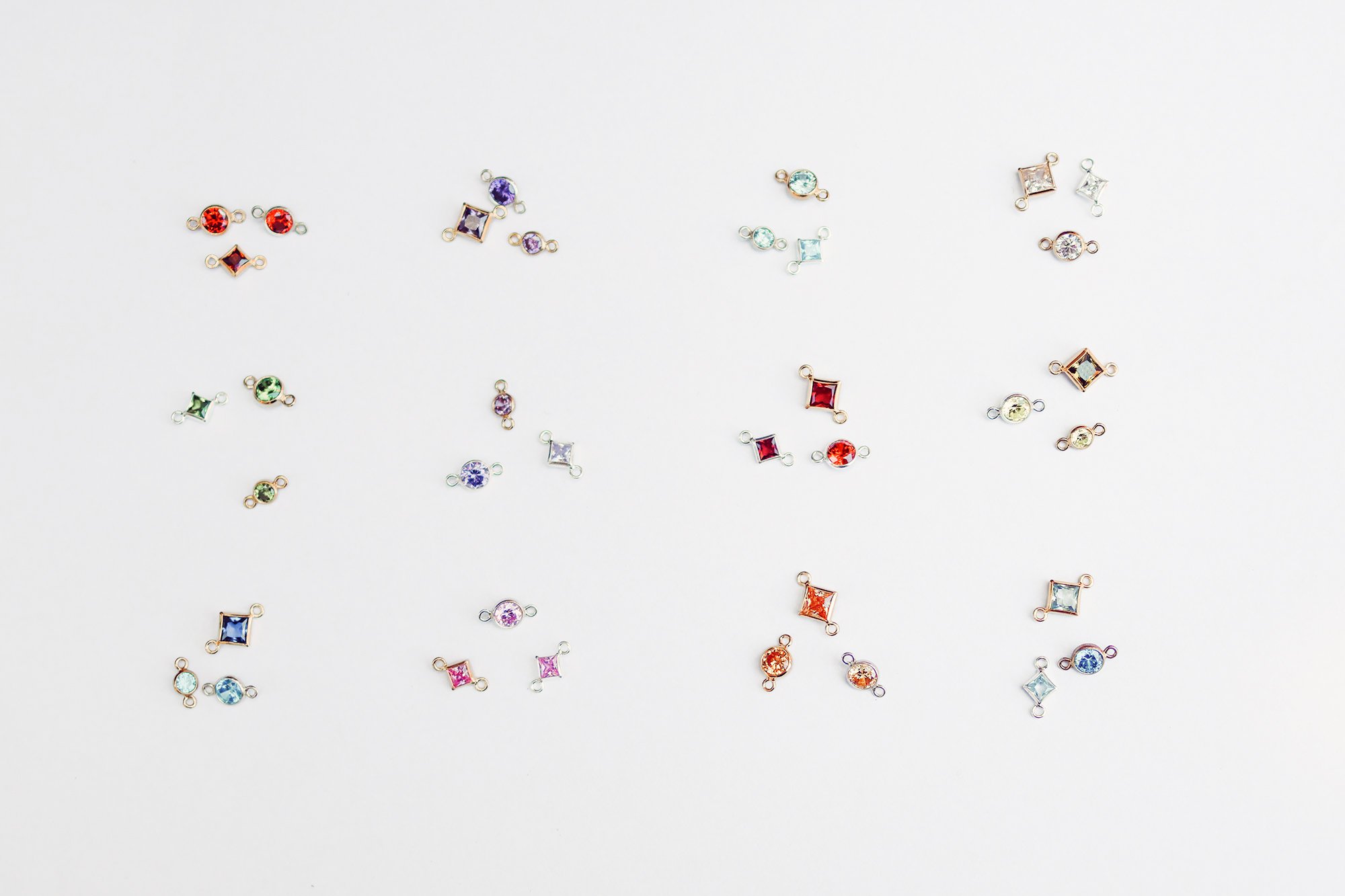 Colorful gemstone and crystal jewelry connectors spread out on a white background.