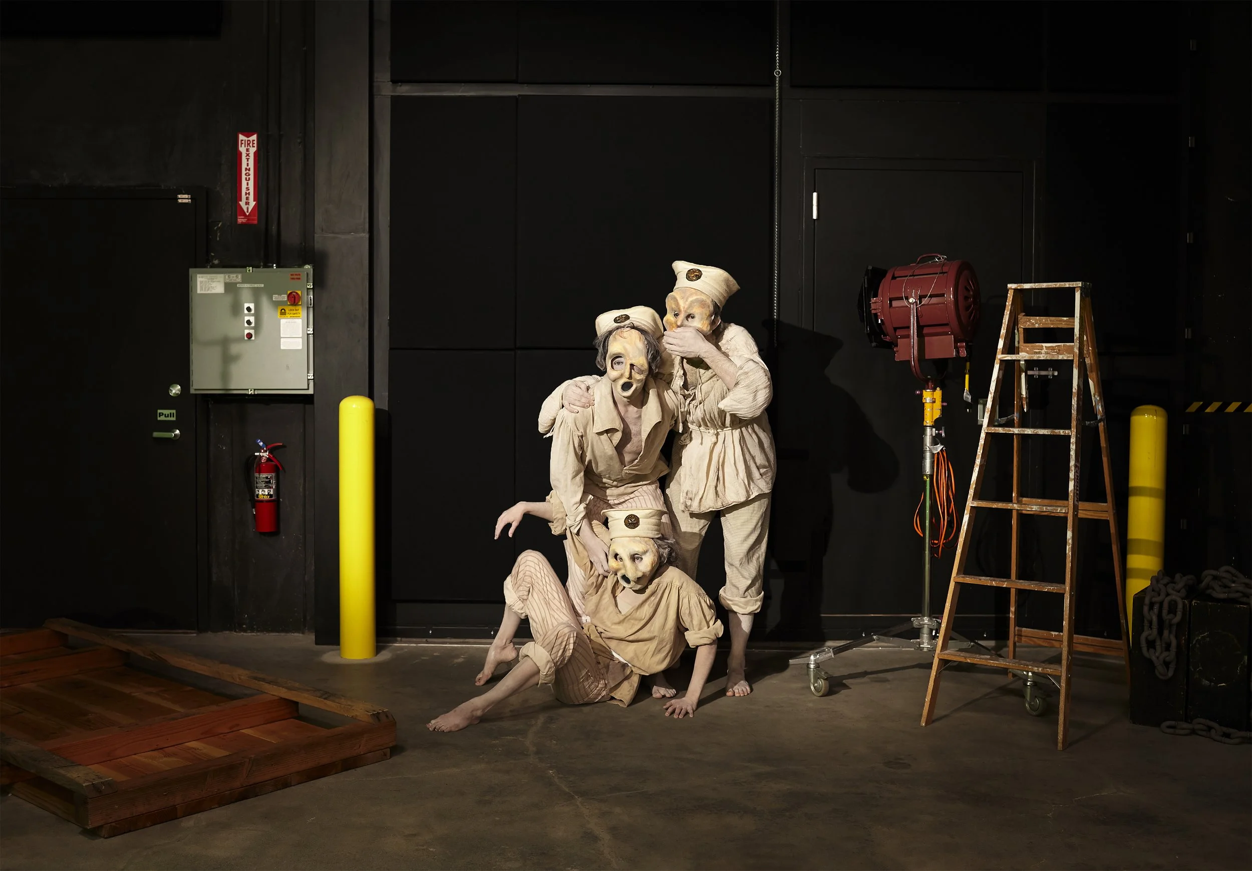 Stage performers wearing dog masks and vintage costumes, posing in front of a black background with theatrical equipment and props. Andrew Fornasier Digital Tech San Francisco
