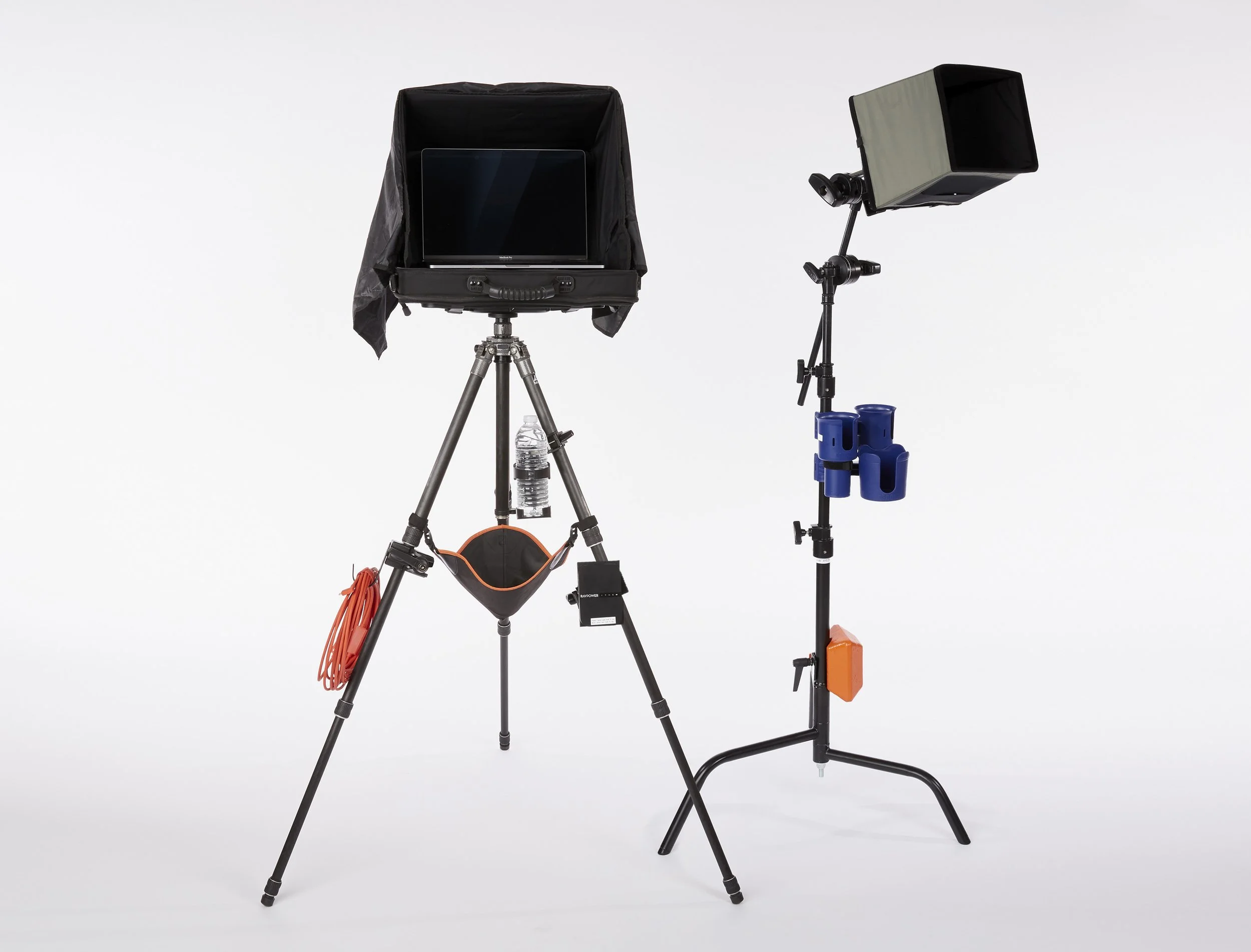 Studio equipment including a camera on a tripod with a black cover, a light with a broad reflector, and power cords, arranged on a plain white background. Andrew Fornasier Digital Tech San Francisco