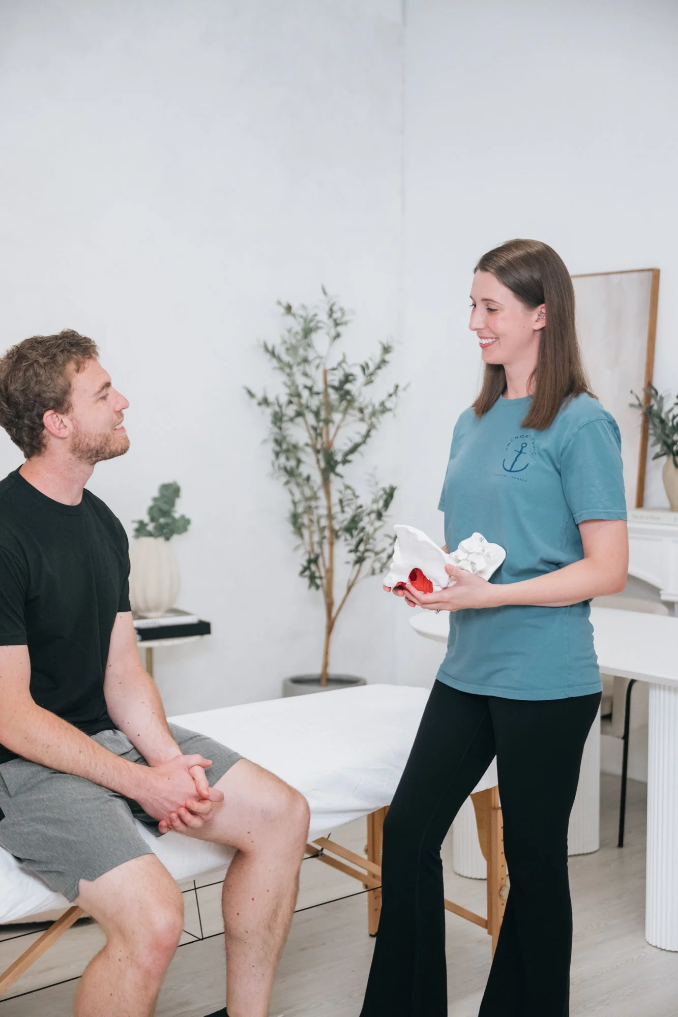 a pelvic therapist using a pelvis model to demo to male patient