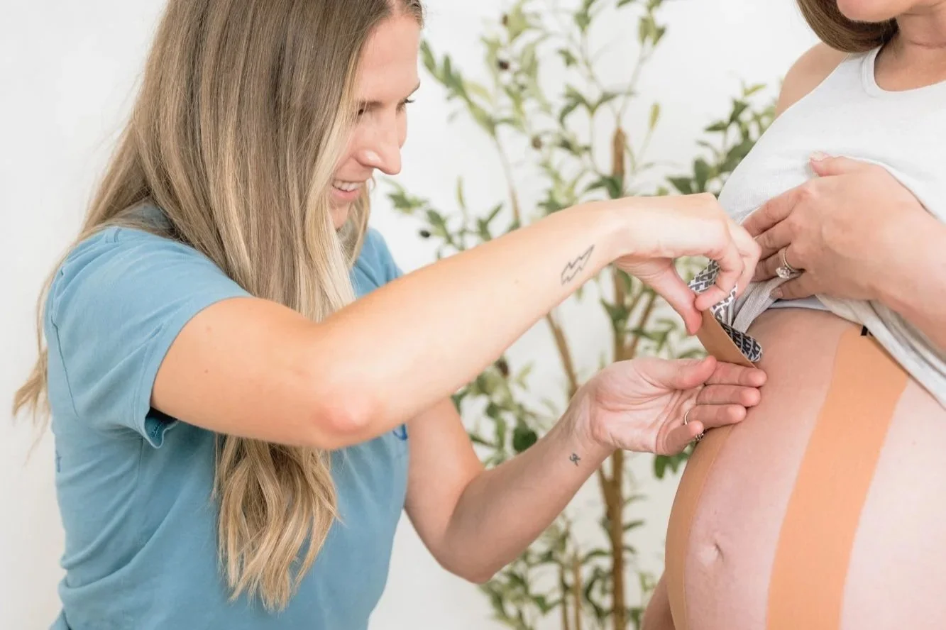 A pelvic floor therapist taping a pregnant belly for support during pregnancy.