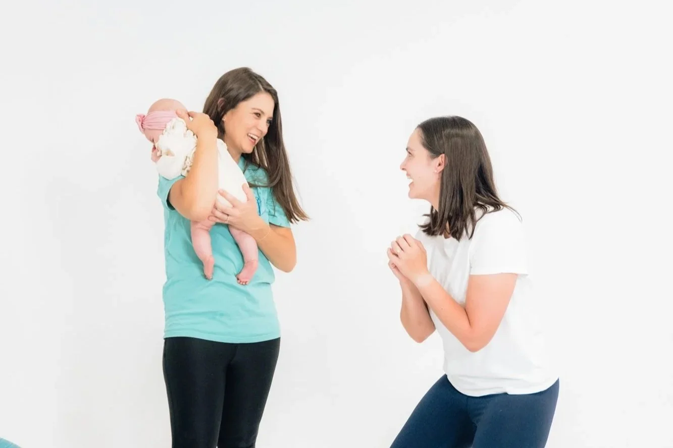 A pelvic floor therapist holding a baby, working with mom postpartum.