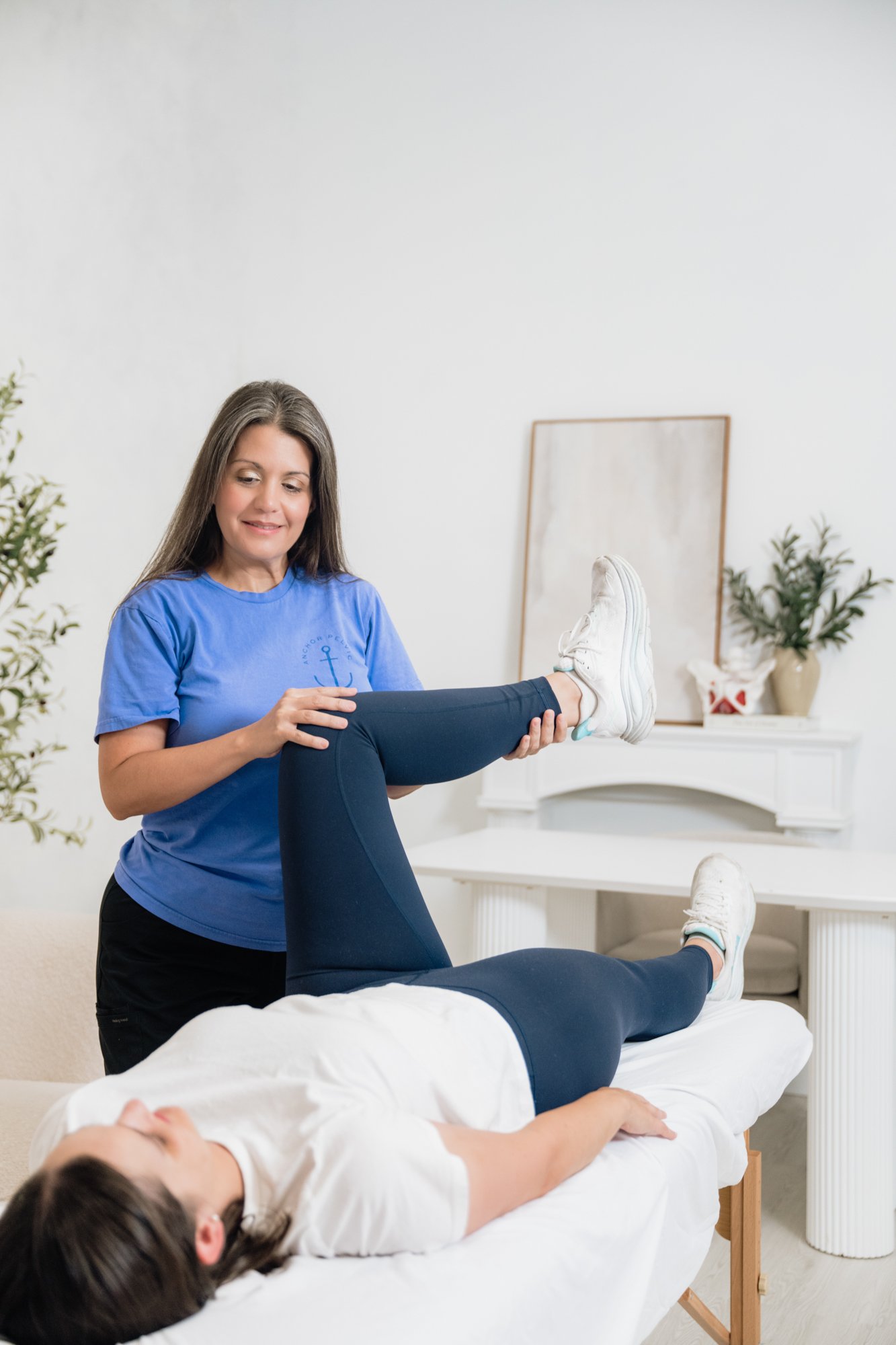 A pelvic floor therapist assessing hip range of motion during a pelvic floor PT session 