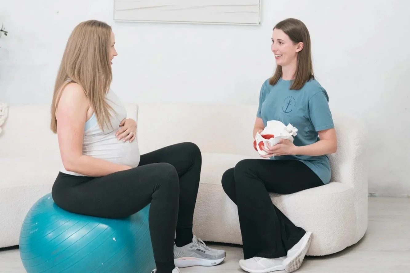 A physical therapist talking to a patient who was sitting on a therapy ball