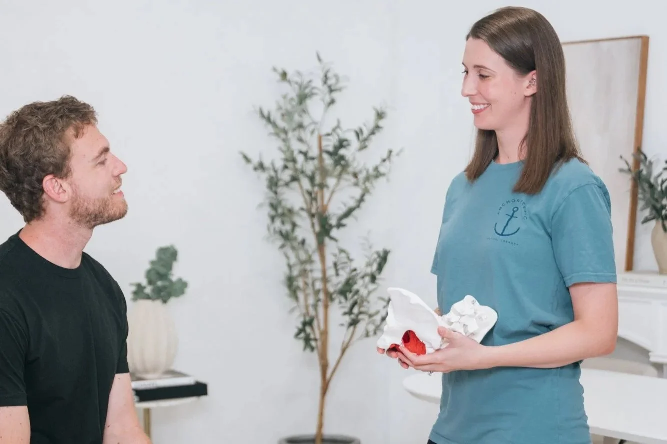 A pelvic floor therapist talking to a male patient. 