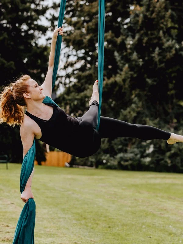 Rochelle performing an aerial silk exercise outdoors in her downtime.