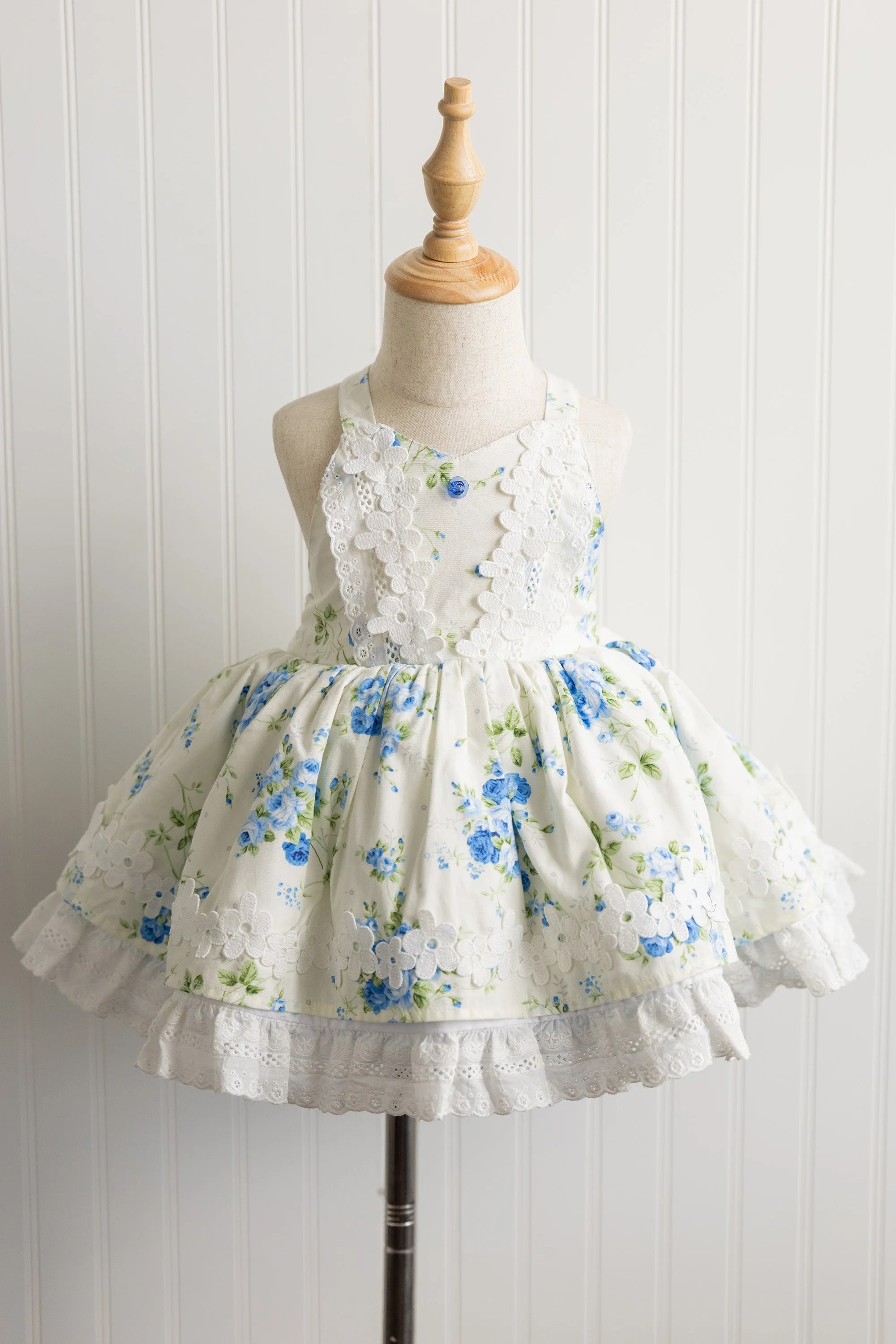 A baby doll dress displayed on a mannequin bust with a wooden top, against a white panel background.