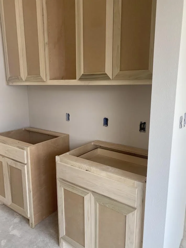 unfinished kitchen cabinets with upper wooden cabinets and lower cabinets without countertops in a new construction kitchen
