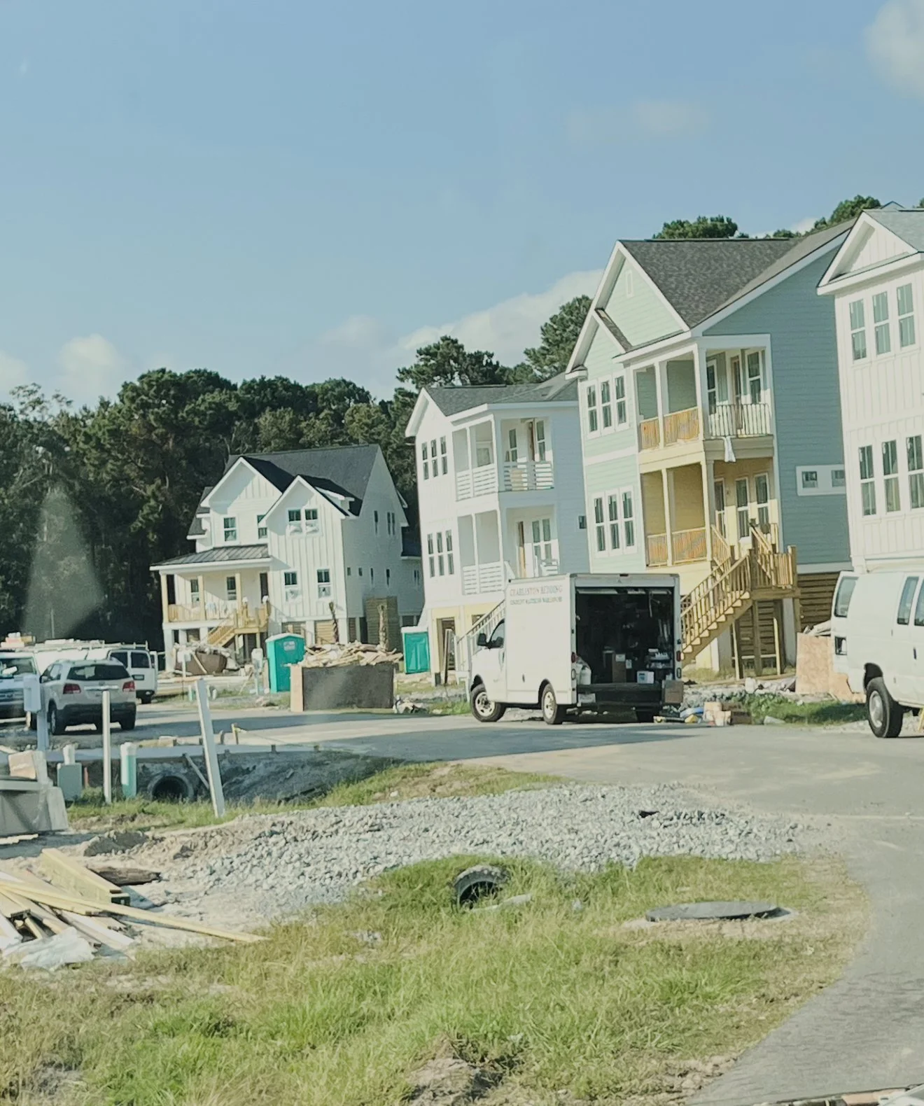 New residential construction site with several multi-story houses in various stages of completion, construction vehicles, and equipment surrounding the area.
