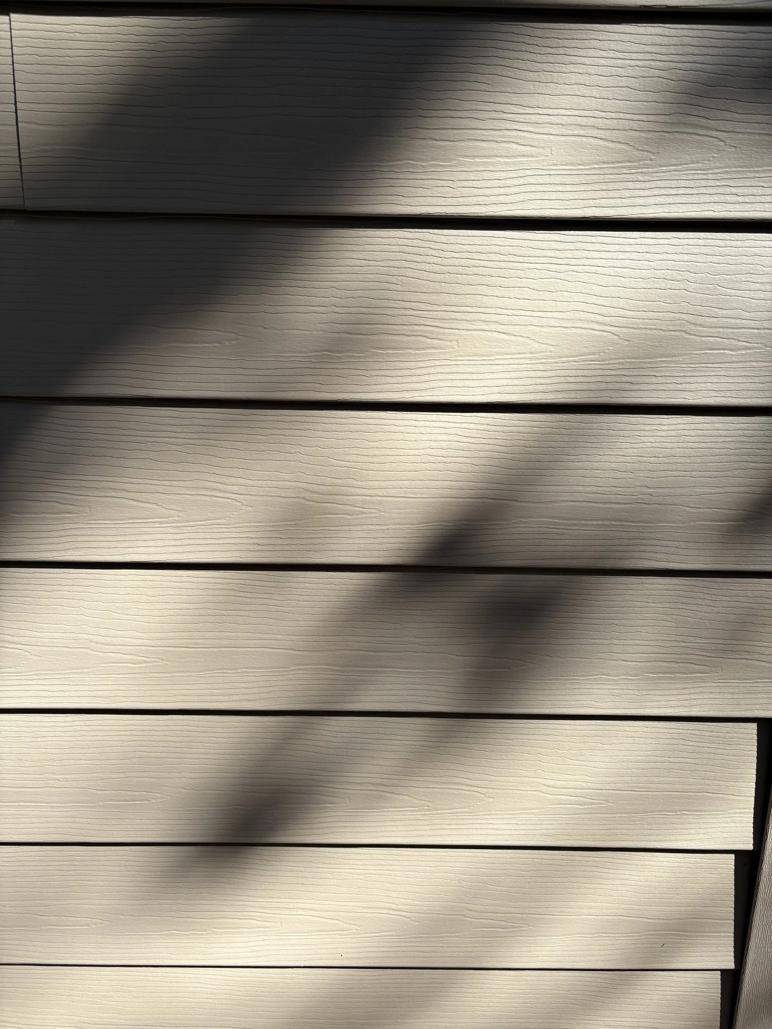 Close-up of horizontal beige wooden panels with shades of light and shadow.