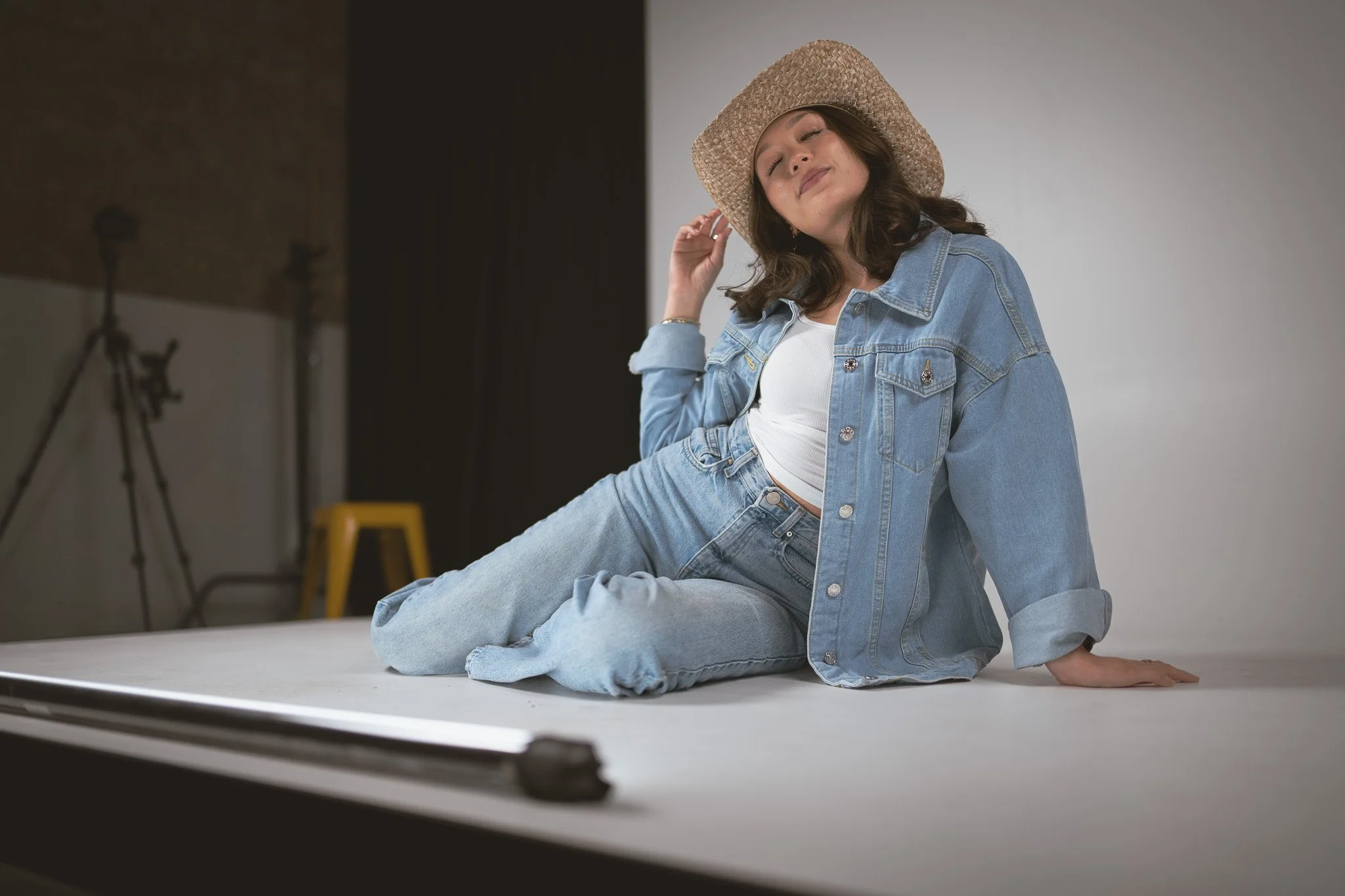 Studio photoshoot of model Victoria during the SXSW Nikon Event in 2026 off Congress. Model is wearing a Canadian Tuxedo (all denim) with her eyes closed, looking upwards, tipping her cowboy hat.